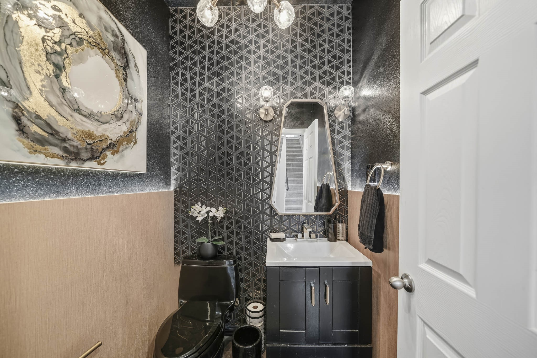 This stylish powder bath makes a bold statement with dramatic geometric tile, rich contrasting finishes, and warm textured wall accents. A sleek vanity, contemporary mirror, and decorative lighting add modern sophistication, while the compact layout maximizes functionality and creates a memorable guest bath.