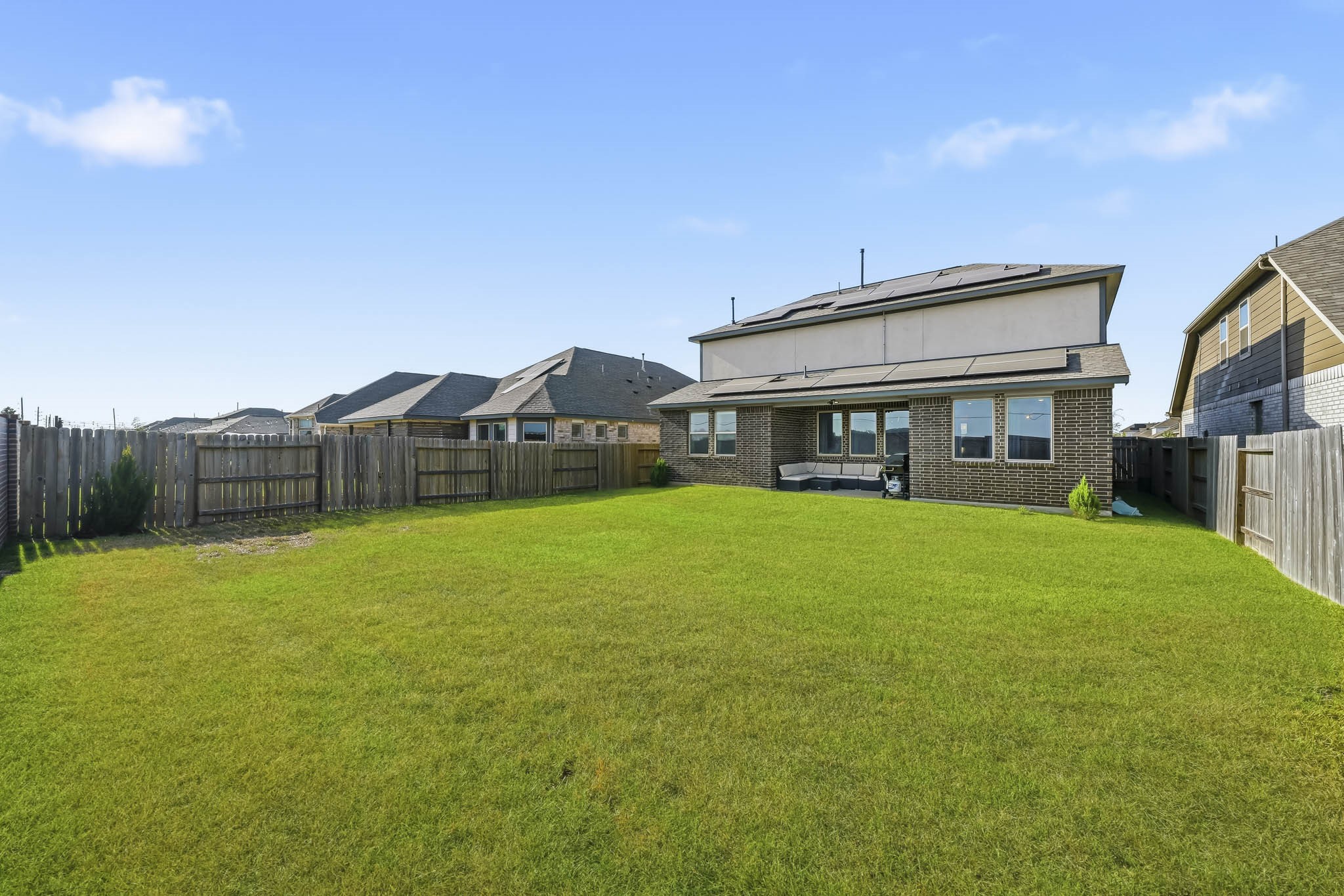 This expansive, fully fenced backyard offers plenty of open green space for outdoor recreation, entertaining, and everyday enjoyment. A covered patio provides a comfortable spot for relaxing or dining outdoors, while the generous lawn easily accommodates a play area with plenty of additional room to enjoy.