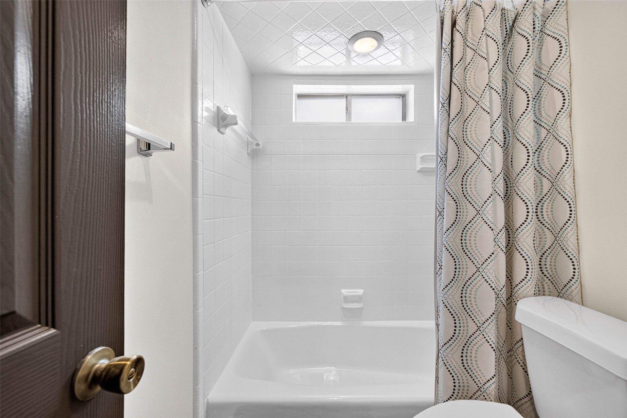 Bathroom tub and shower with a subway tile surround, a high window, and a deep tub.