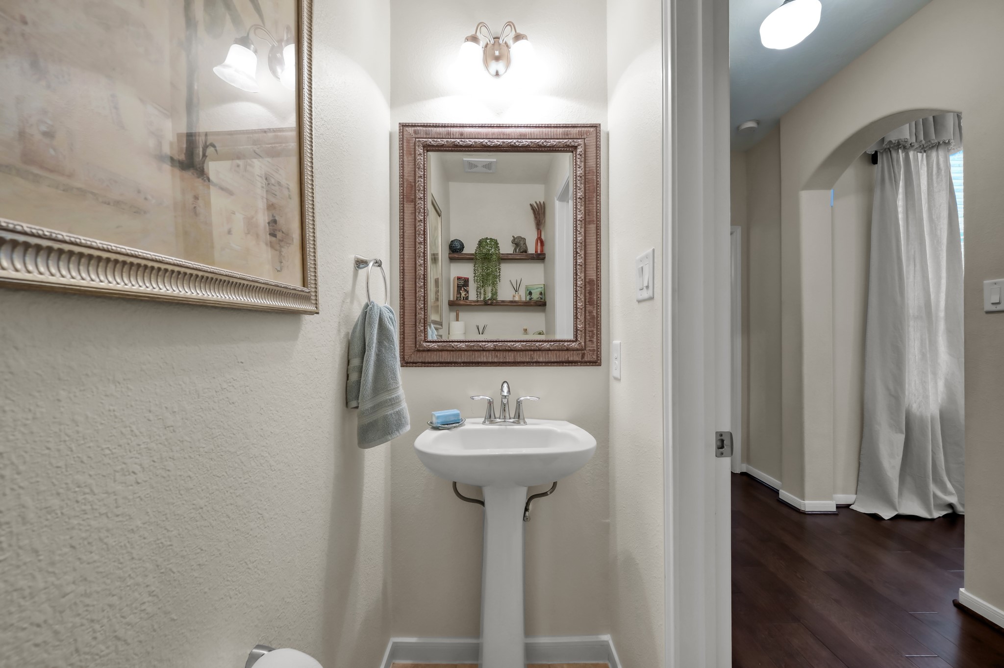Charming guest powder bath with pedestal sink, decorative mirror, and a warm, inviting feel for visitors.