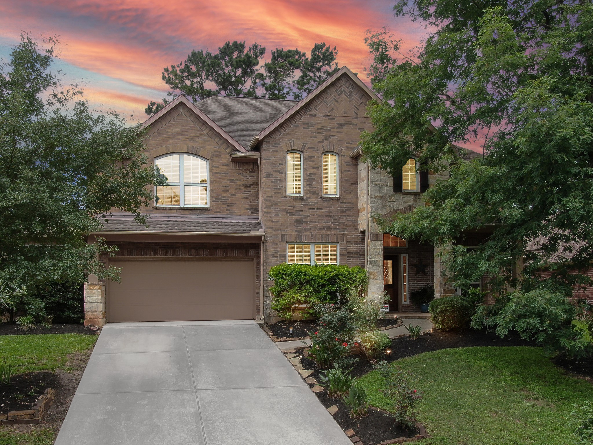 Welcome home! This beautiful brick and stone two-story sits on a quiet, tree-lined street with gorgeous curb appeal and warm evening charm. Mature landscaping, a long driveway, and inviting front elevation make a stunning first impression.