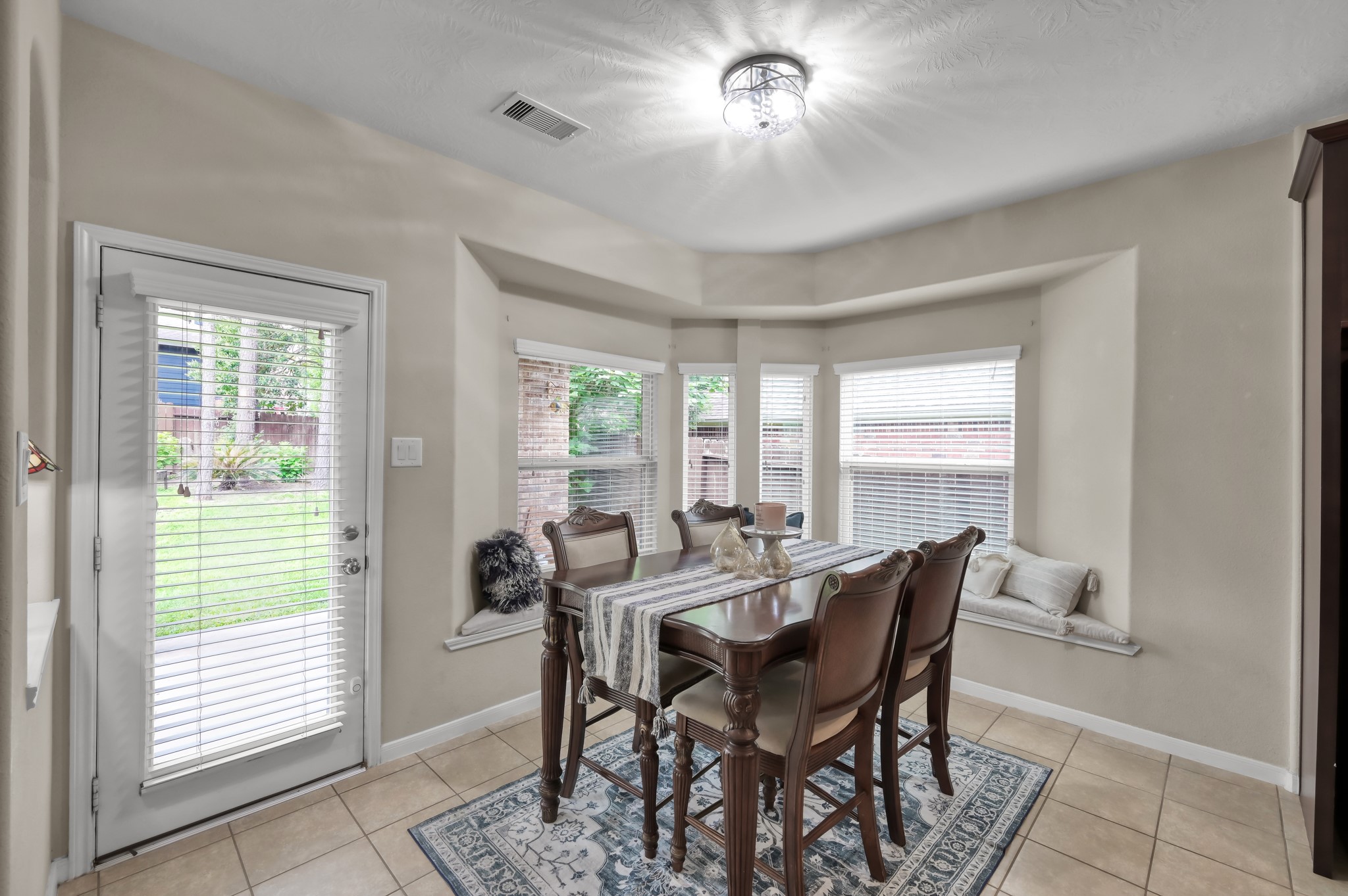 Enjoy morning coffee or family meals in this inviting breakfast area featuring large windows, built-in seating, and peaceful backyard views.