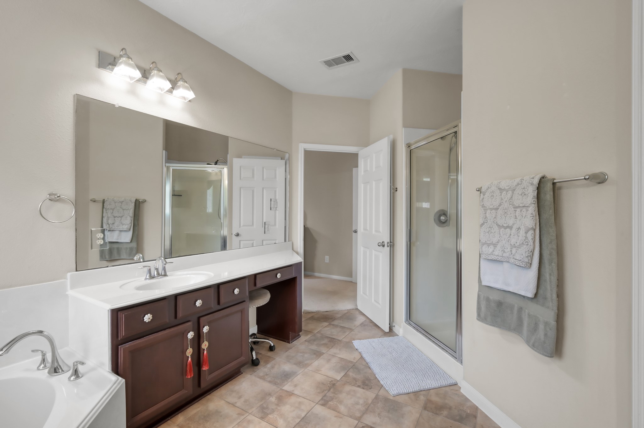 Well-appointed primary bath with dual vanities, ample counter space, and a separate glass-enclosed shower. Functional layout with plenty of storage and natural light.