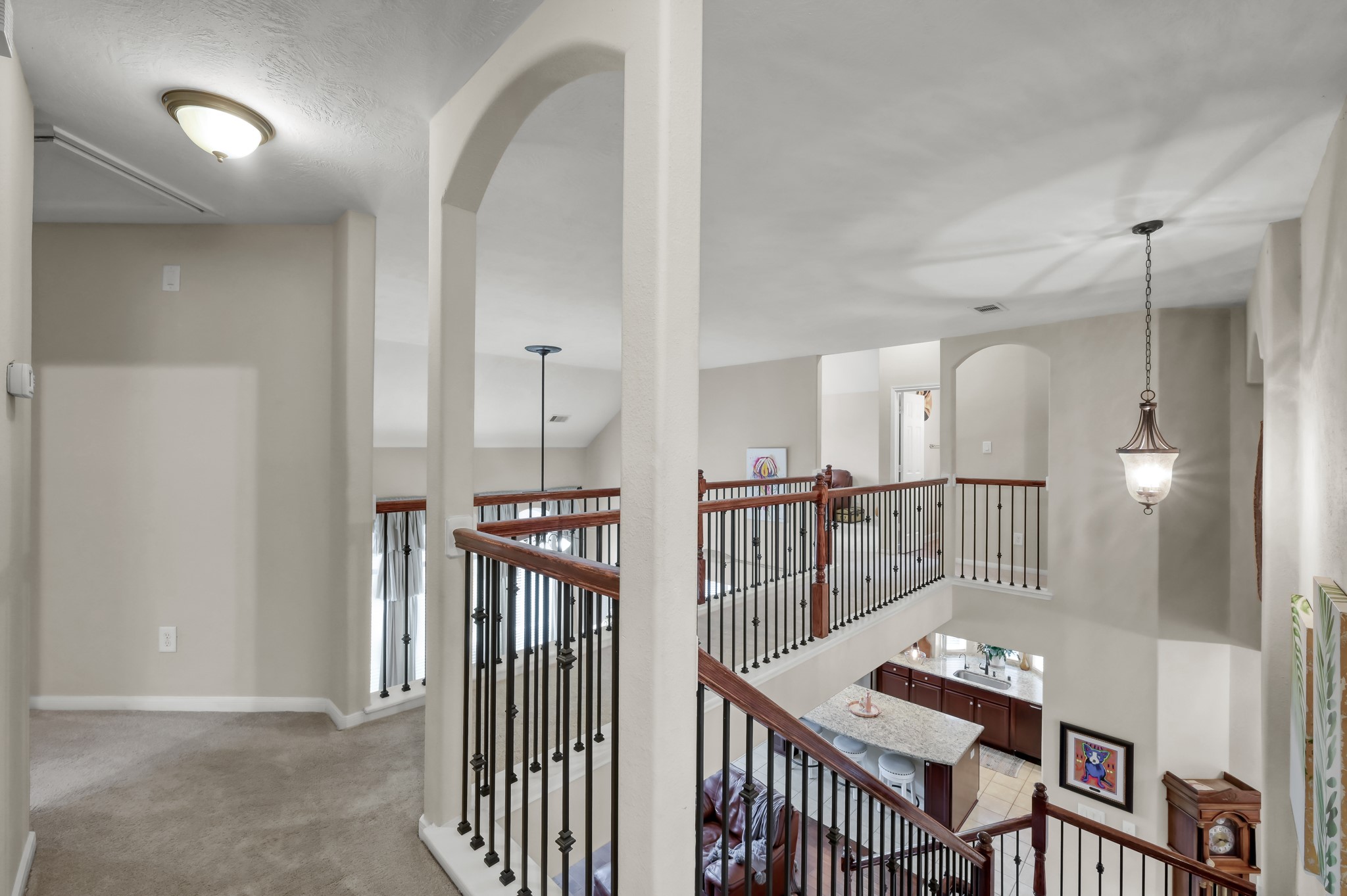 Beautiful open upstairs landing overlooking the main living area below, featuring elegant iron railing details and plenty of space for a reading nook or flex area.