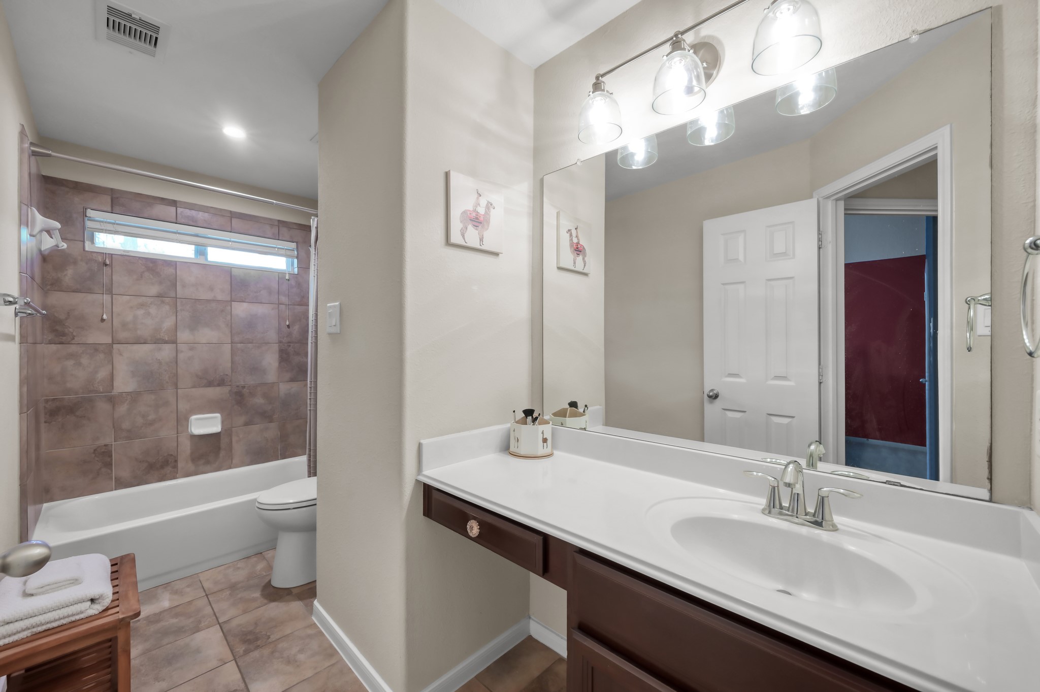 Bright and clean full bathroom with large vanity, generous mirror space, and tiled tub/shower combo.