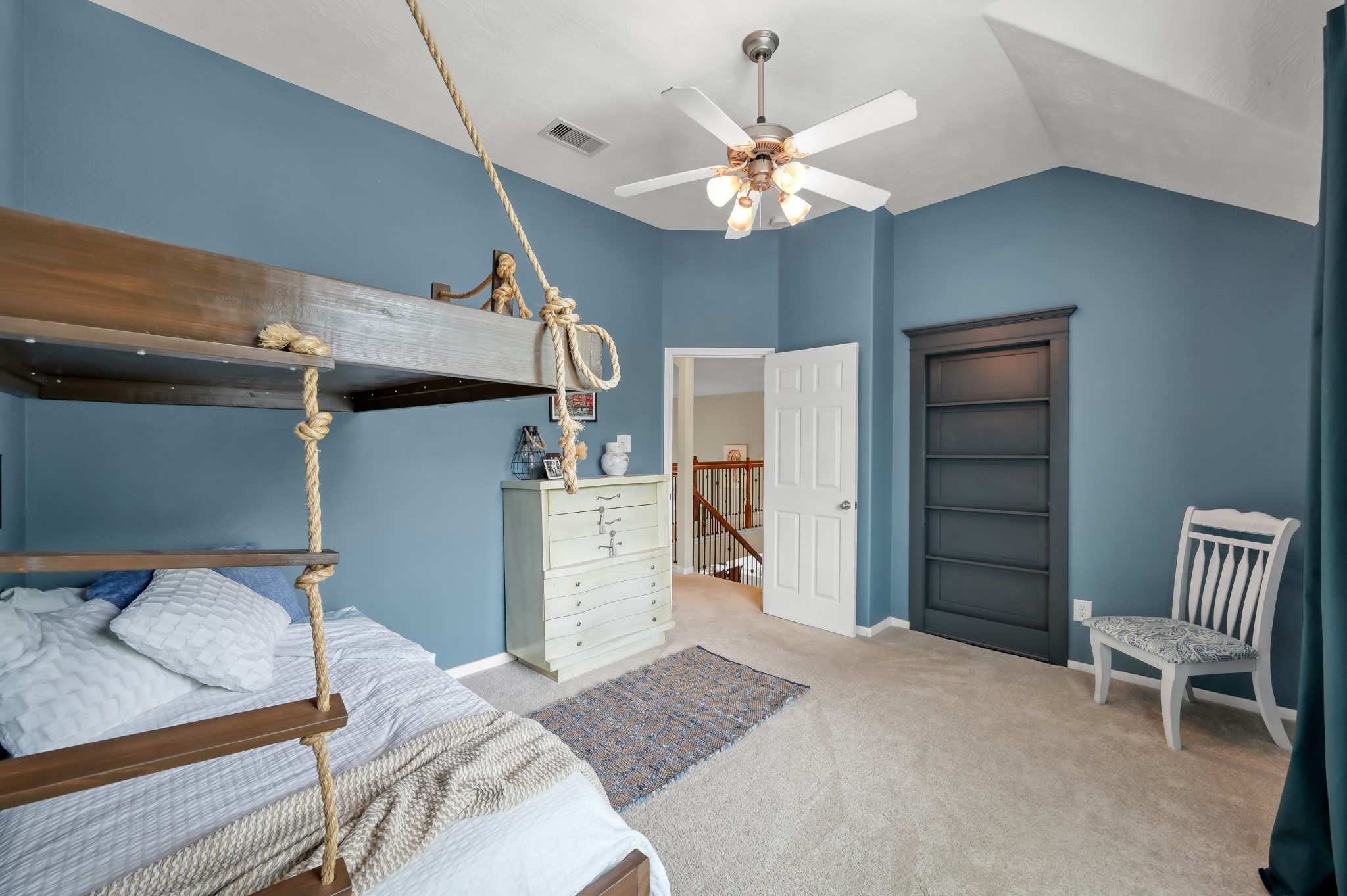 Fun and stylish bedroom with soaring ceilings, custom rope-style bunk beds, built-in shelving, and plenty of room to personalize the space.