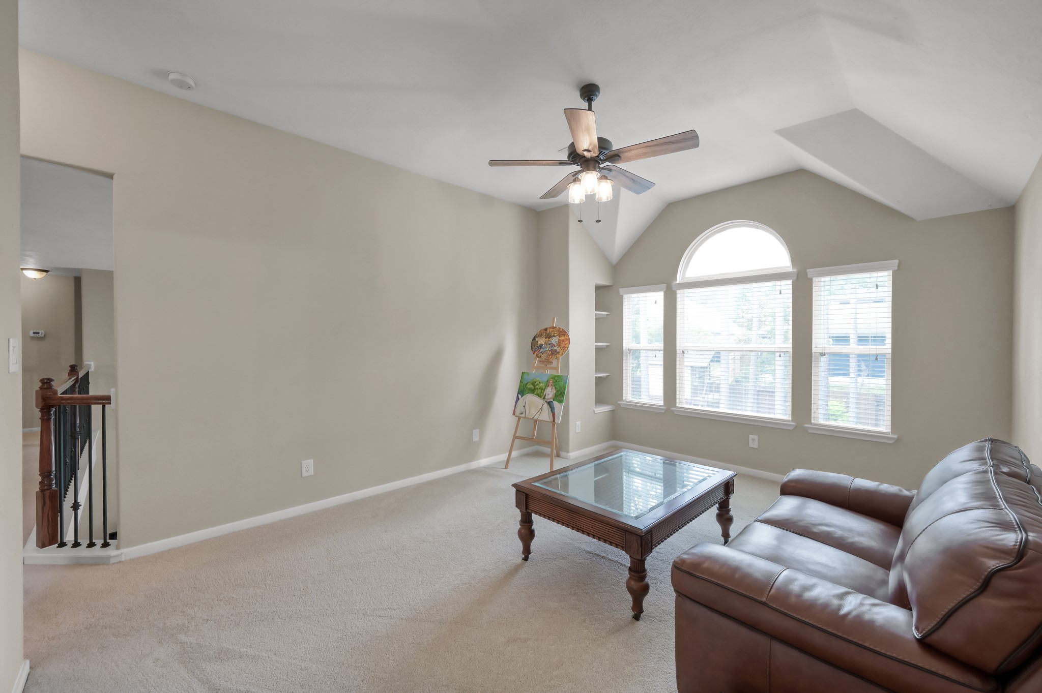 Versatile upstairs living area perfect for a game room, media space, home office, or playroom with beautiful natural light and vaulted ceilings.