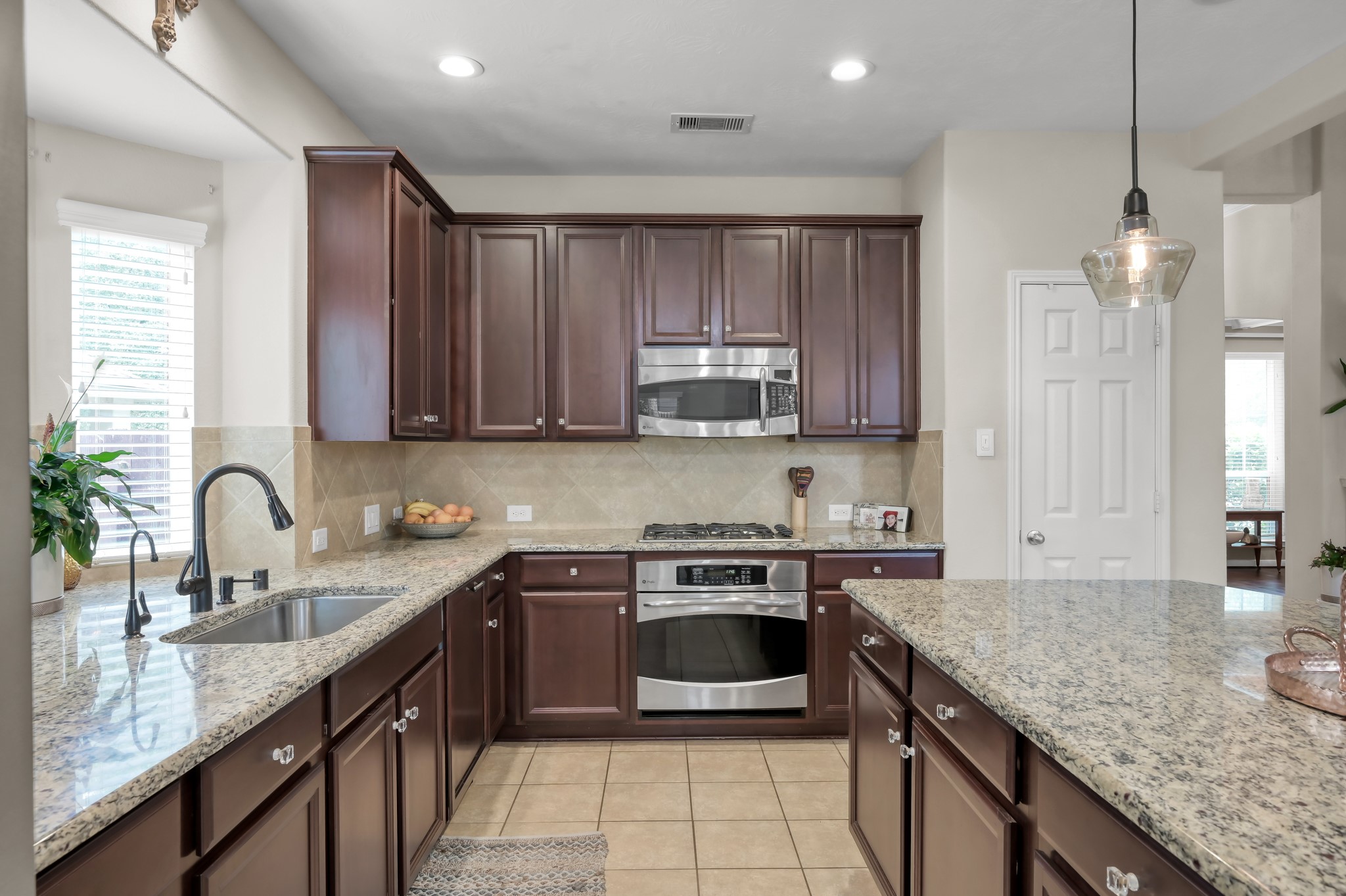 Beautiful granite countertops, rich cabinetry, stainless steel appliances, and plenty of prep space make this kitchen both stylish and functional. A perfect setup for everyday cooking and hosting guests.