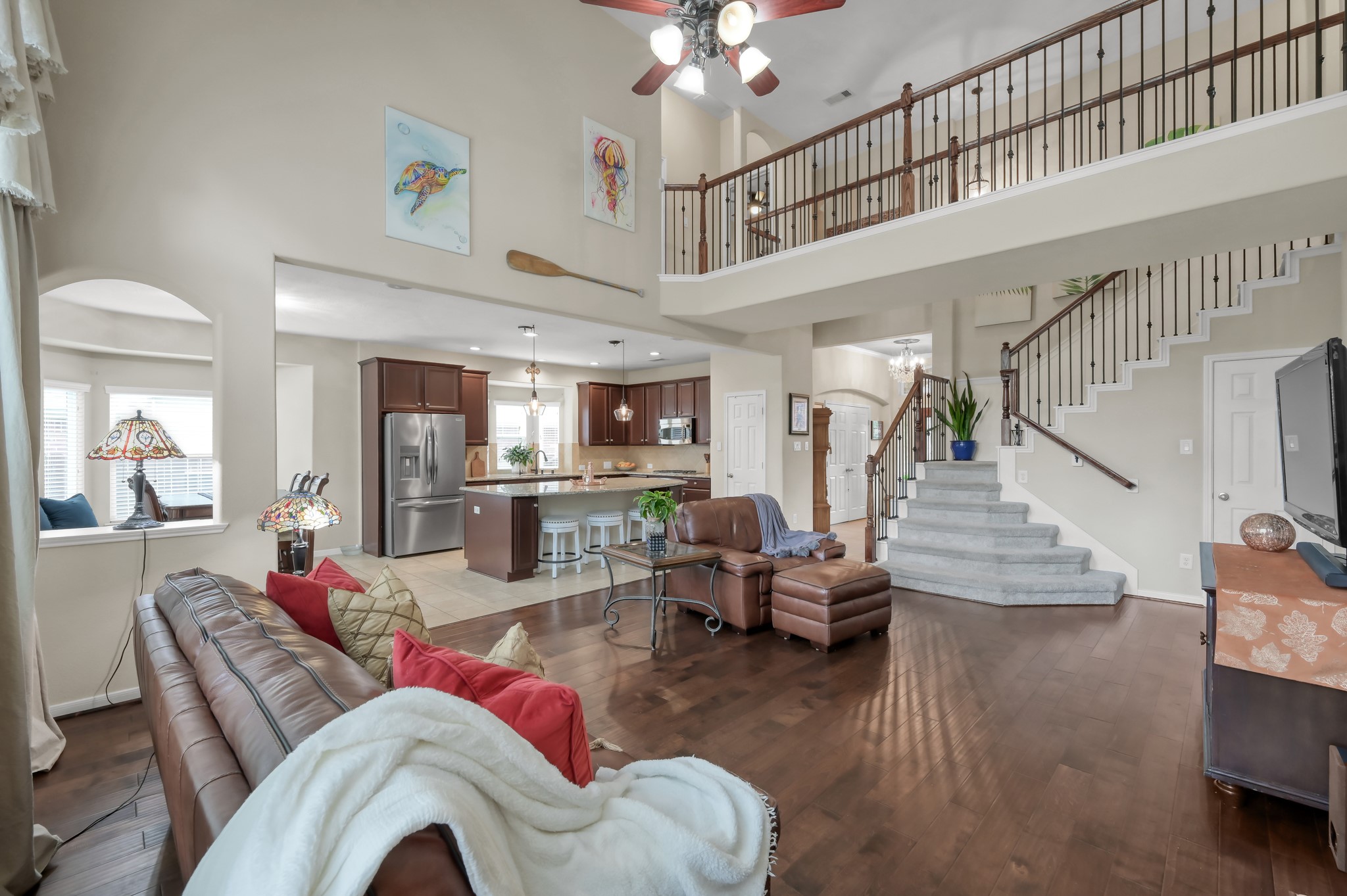 This stunning main living room also features dramatic two-story ceilings, elegant staircase details, and an open layout that creates a bright and welcoming atmosphere throughout the home.