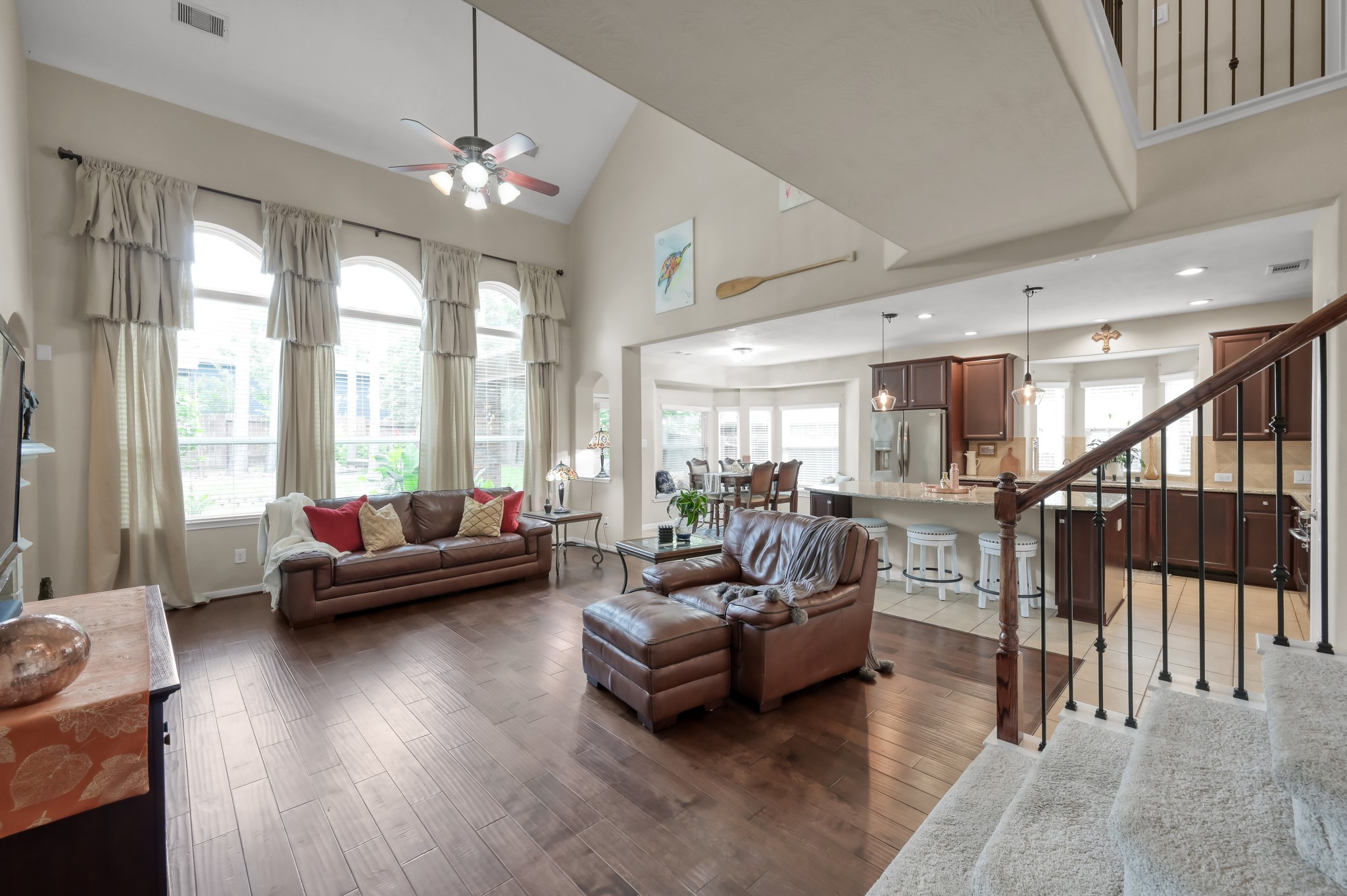 Spacious open-concept living area with soaring ceilings, beautiful wood floors, and oversized windows that fill the home with natural light. Perfect for everyday living and entertaining with an easy flow into the kitchen and breakfast area.
