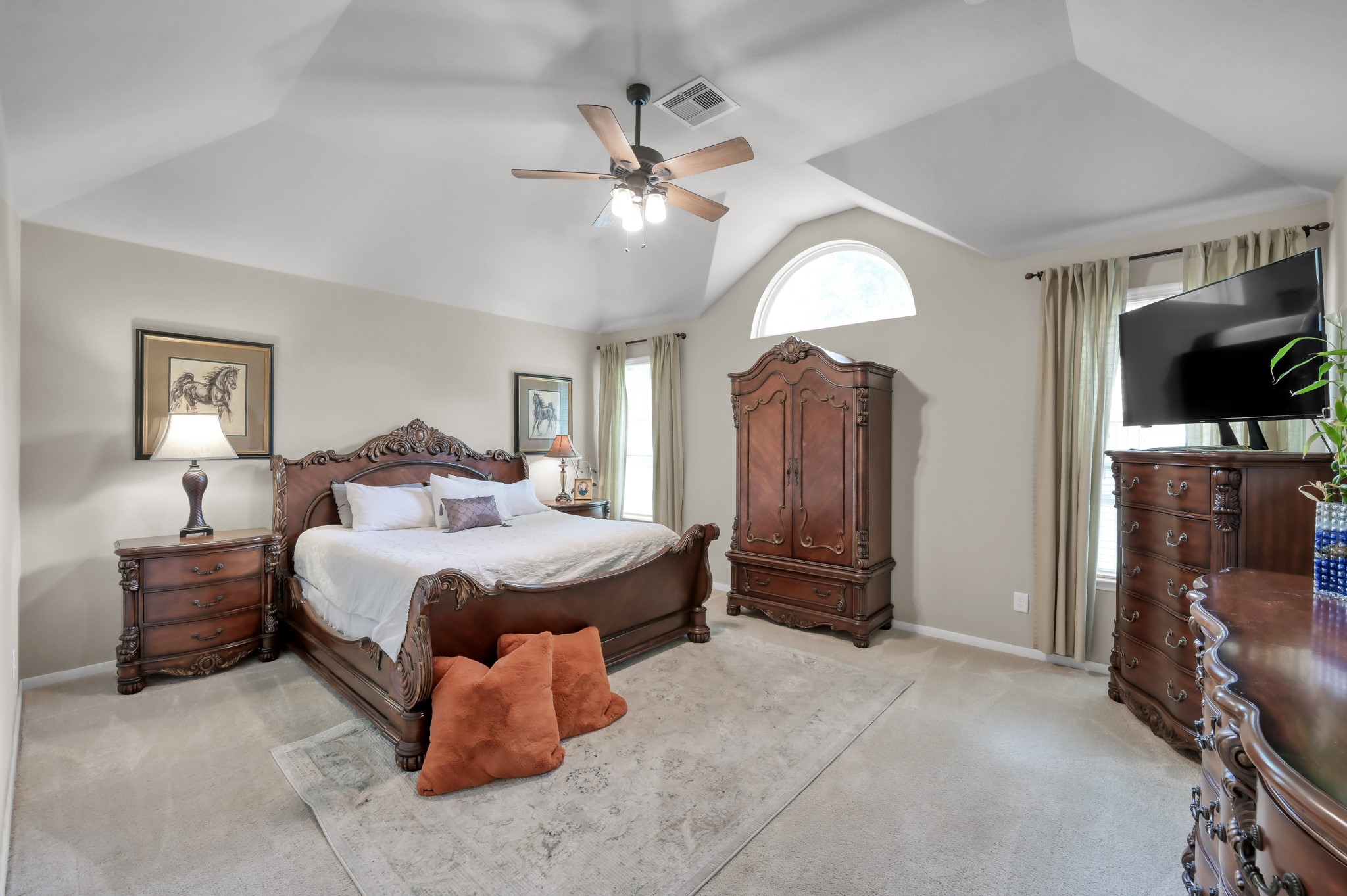 This oversized primary bedroom features elegant architectural ceilings, large windows, and a bright, airy layout designed for comfort and relaxation.