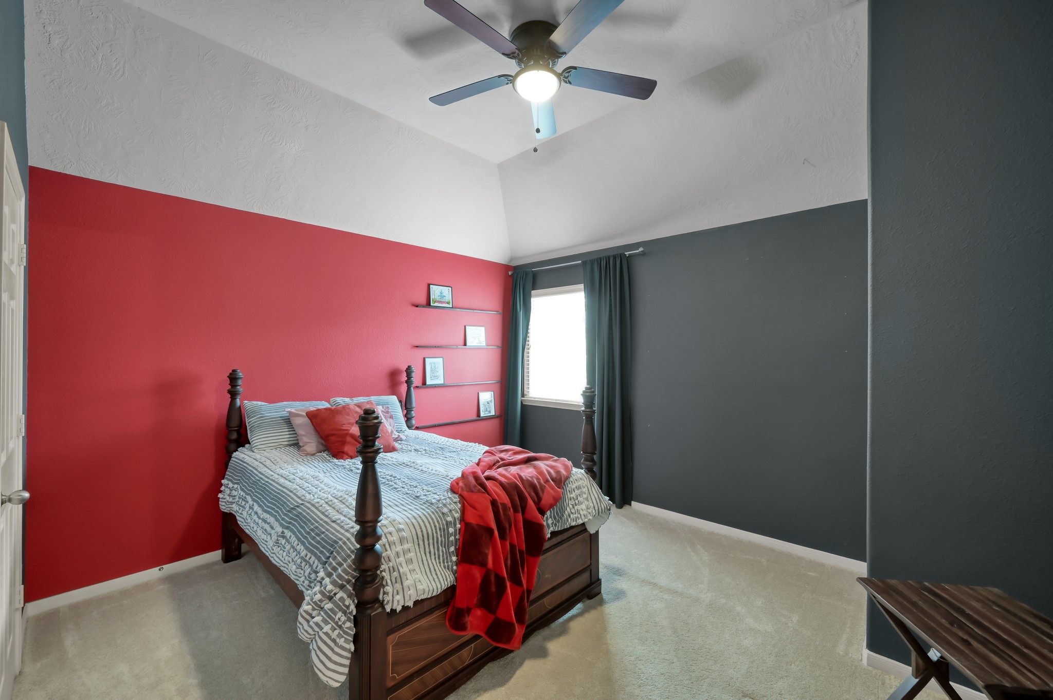 Stylish bedroom with vaulted ceilings, bold designer-inspired accent walls, and a cozy layout filled with natural light.