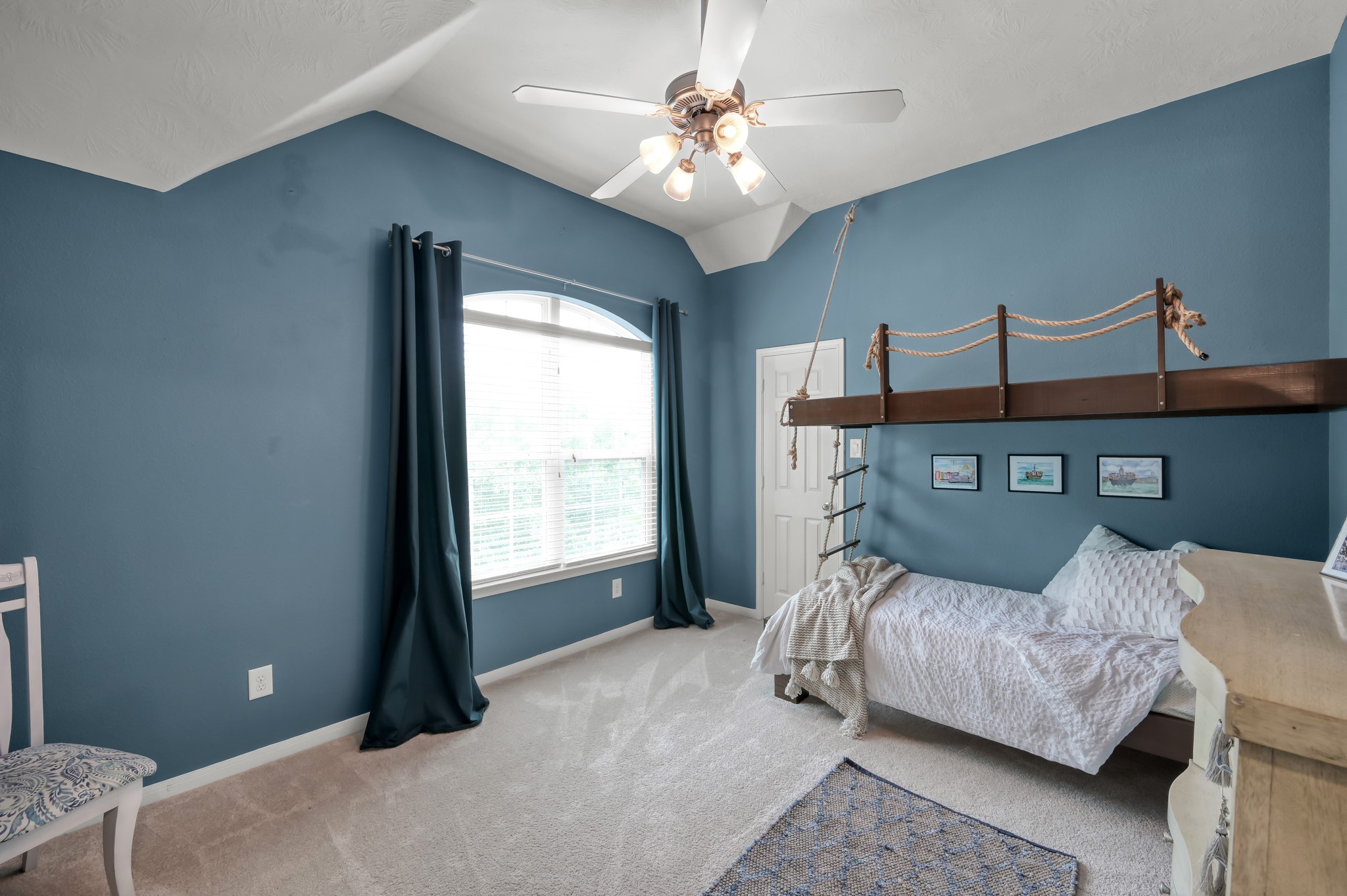 Bright and spacious bedroom featuring vaulted ceilings, large windows for natural light, and unique built-in custom bunk bed details that add character and charm.
