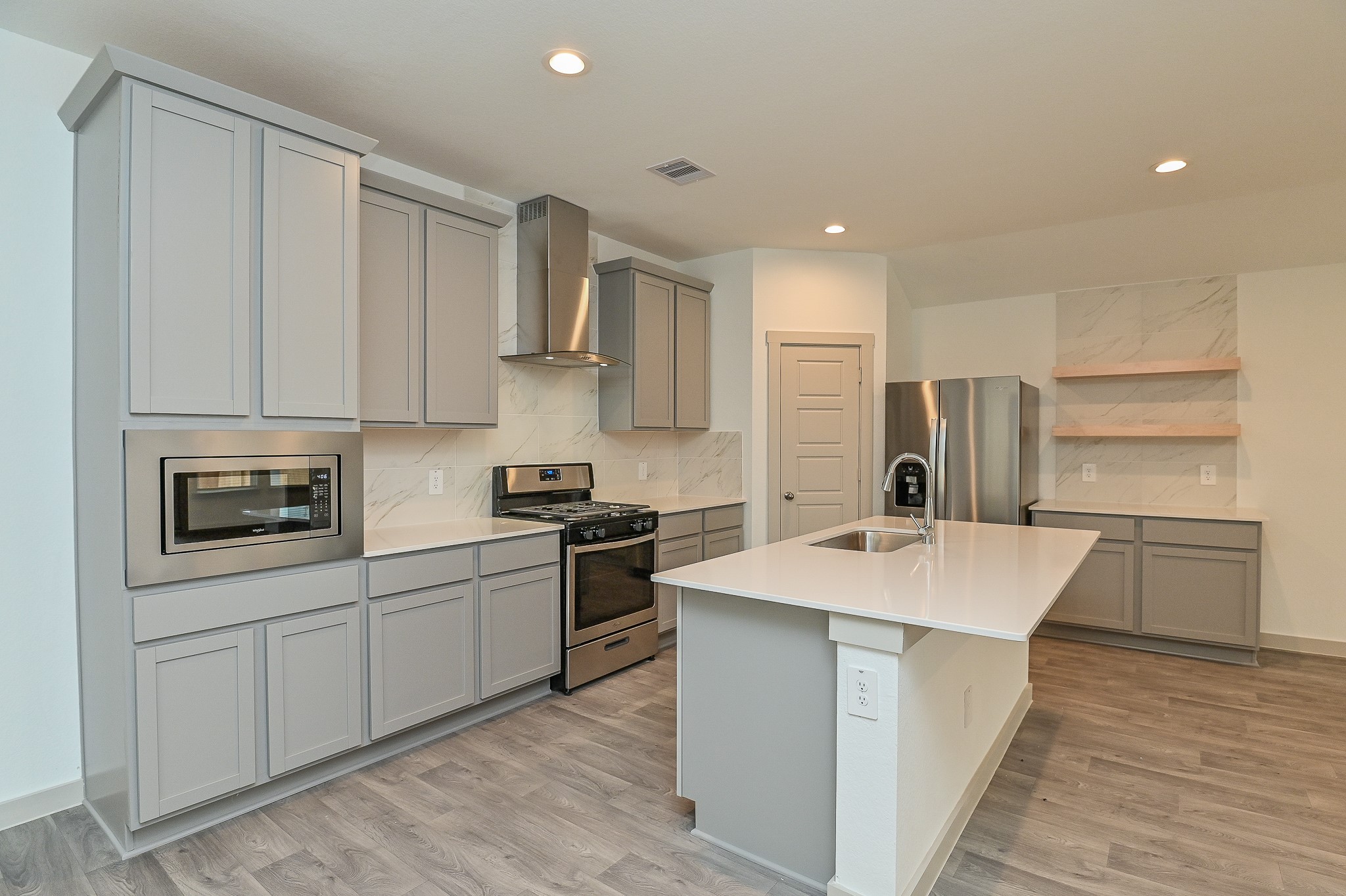 White or gray quartz countertops, bar seating, floating shelves and stainless steel appliances White or gray quartz countertops, bar seating, floating shelves and stainless steel appliances
