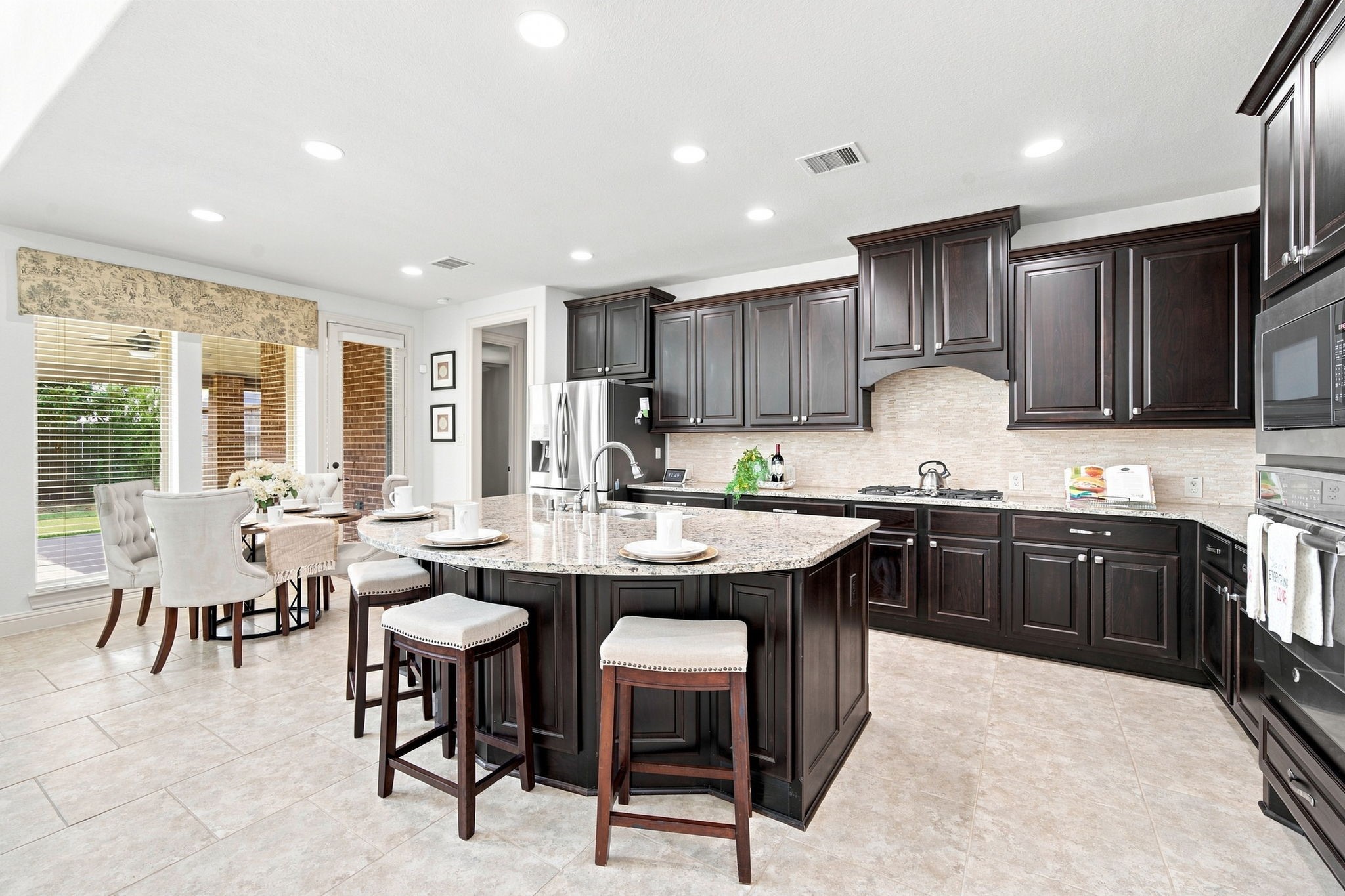 Chef-inspired kitchen with rich espresso cabinetry, granite countertops, and a spacious curved island perfect for gathering and entertaining.
