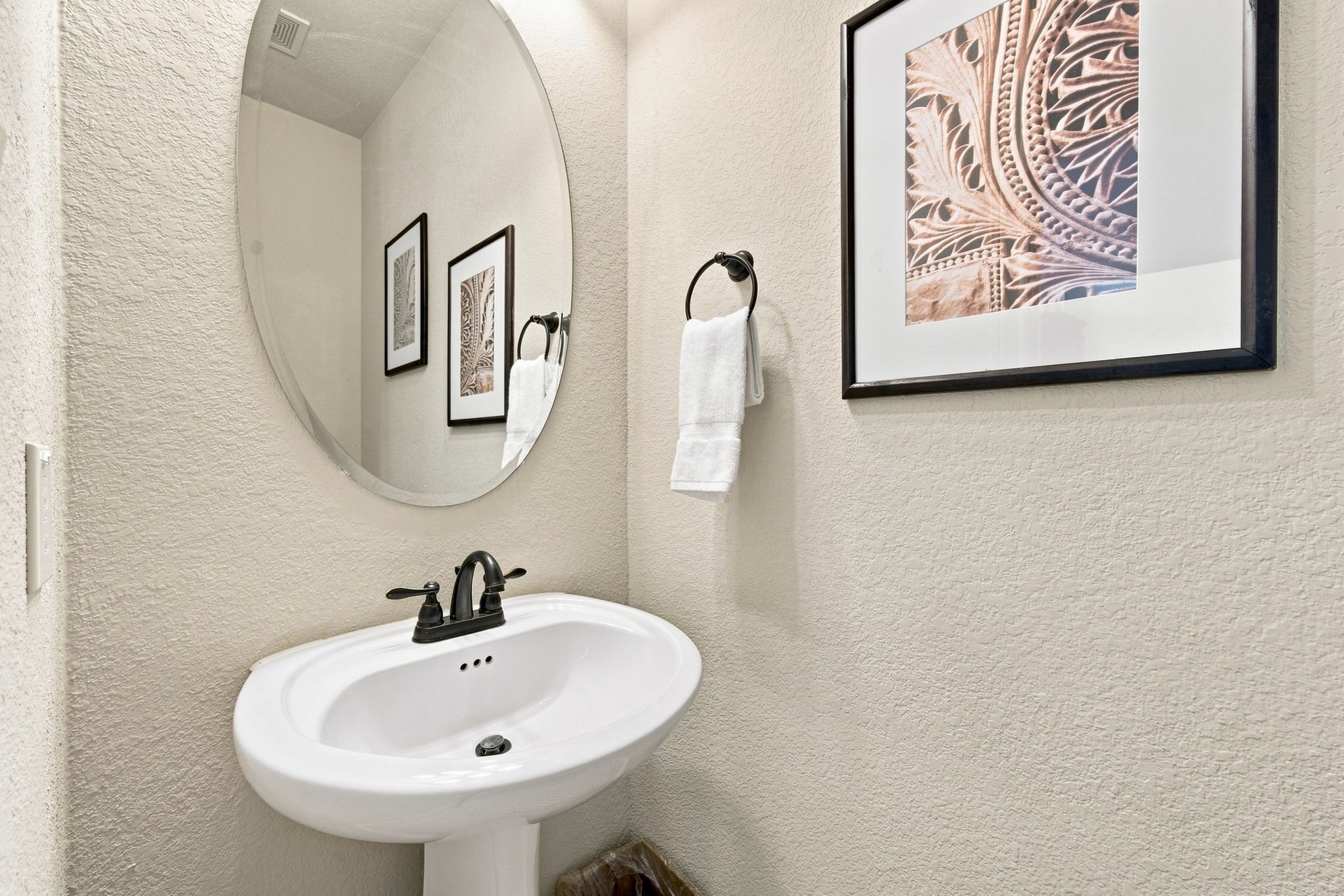 Charming half bath with a pedestal sink, and oil-rubbed bronze fixtures.
