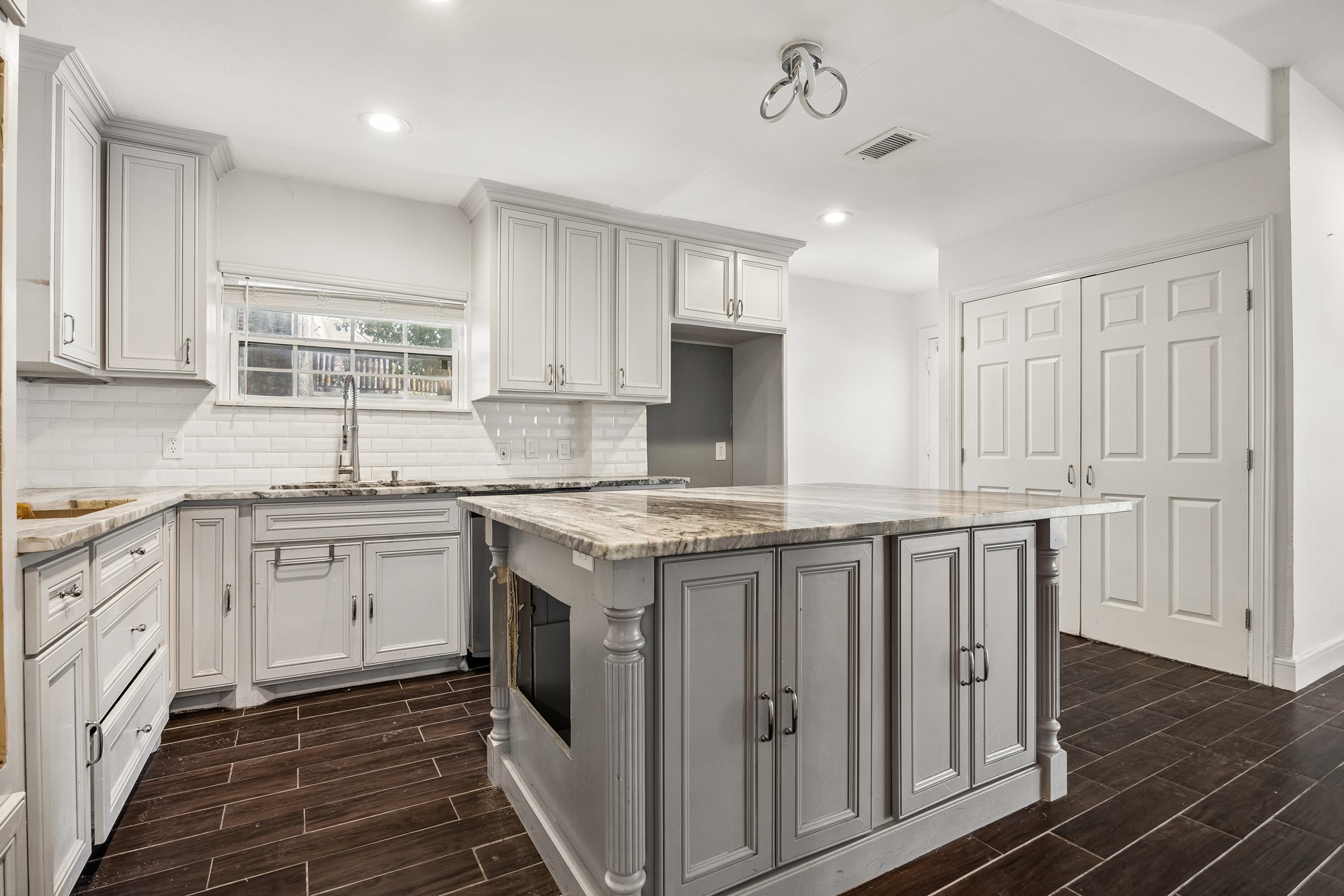 Kitchen with island, subway tile backsplash and pantry.