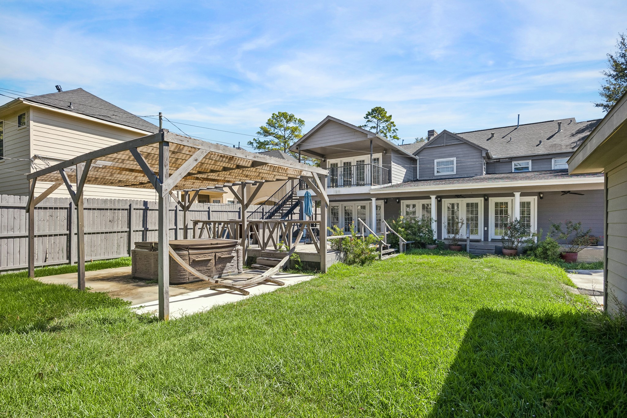 Backyard with pergola, deck and green lawn.