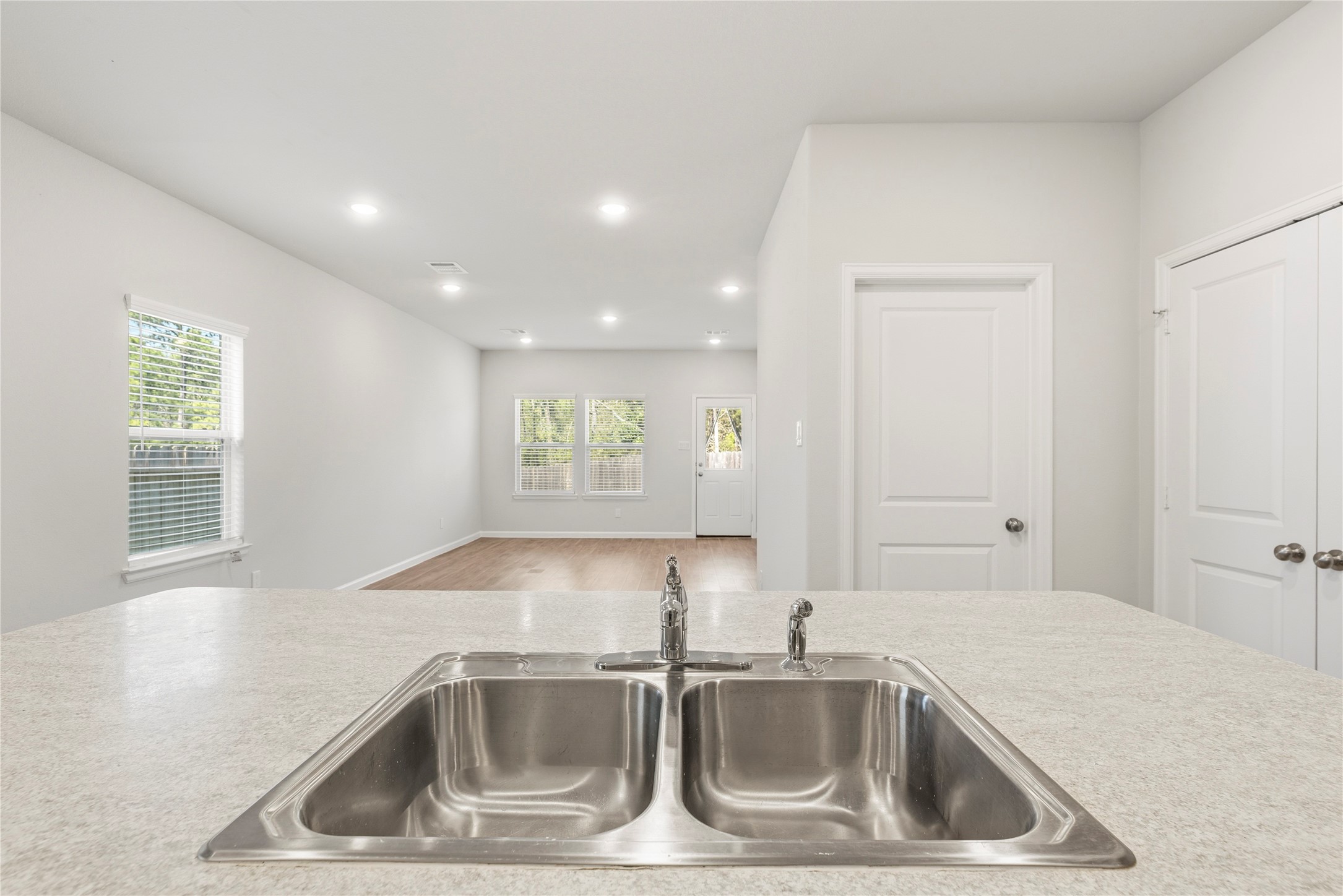 The view from the kitchen sink reaches across the living area to the rear windows and back doora pleasant outlook while handling everyday kitchen tasks.