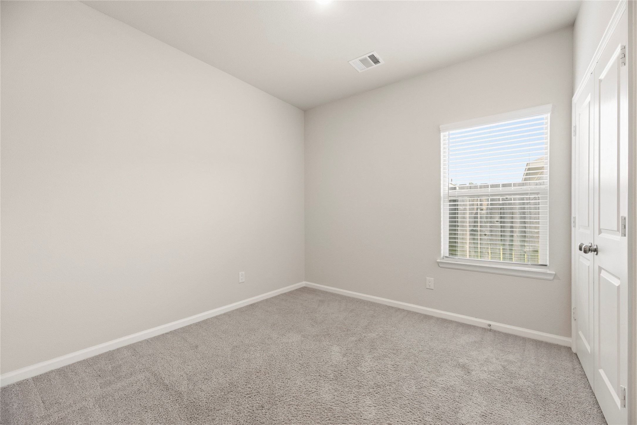 This additional bedroom offers a neutral backdrop and carpeted comfort, with closet storage and a window bringing in natural light.
