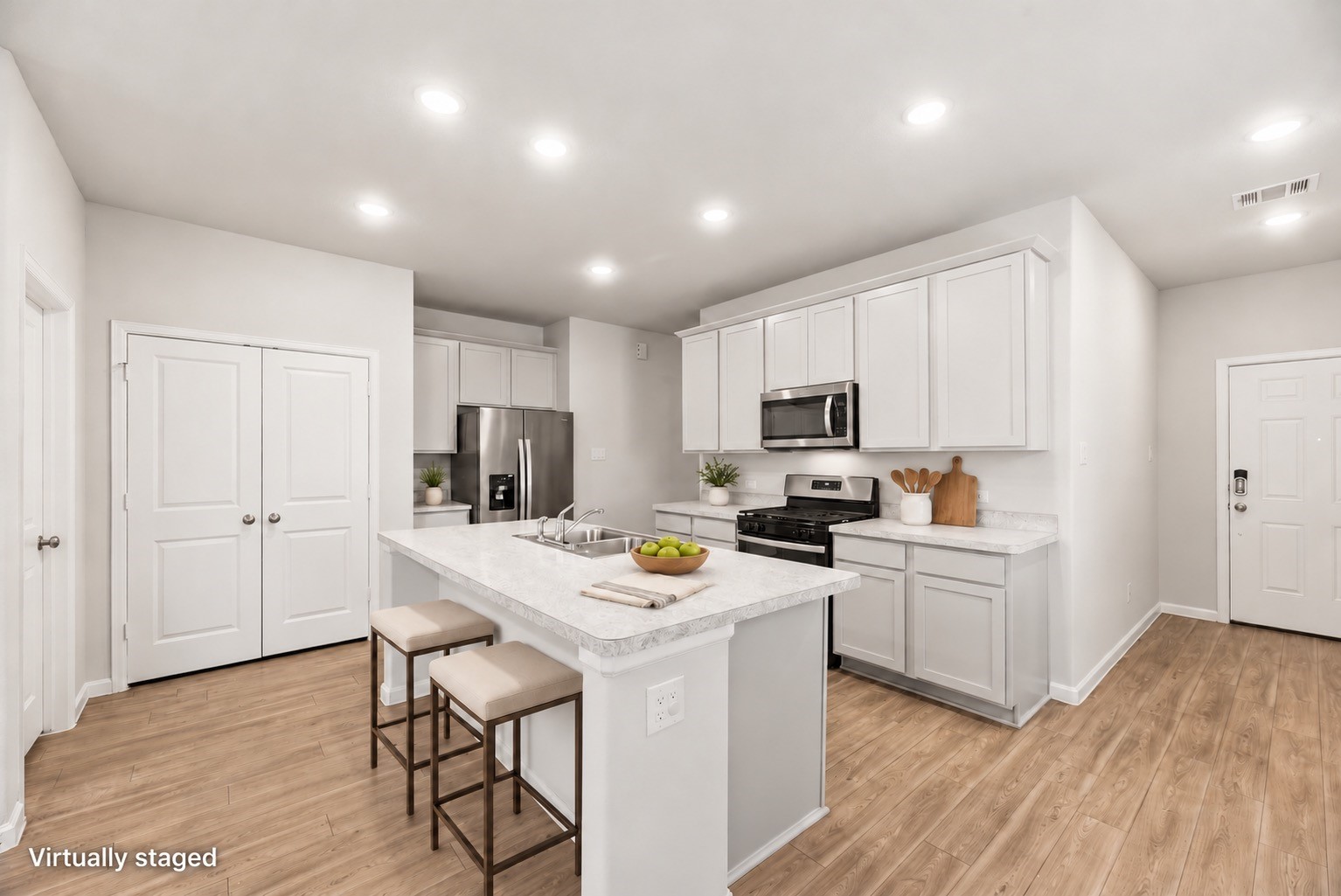 A few thoughtful touches show how the island can serve as an everyday gathering spot, with white cabinetry and stainless-steel appliances completing the kitchen. Furniture and decor are virtually staged; original photo included.