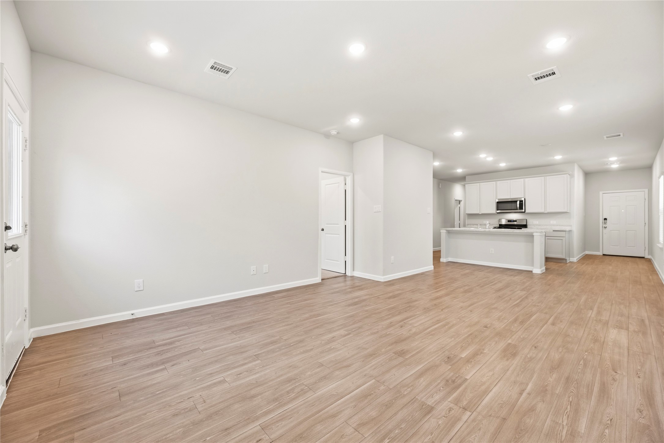 Enjoy a connected layout with room to arrange a comfortable seating area close to the kitchen. Recessed lighting and consistent flooring help the space feel cohesive.