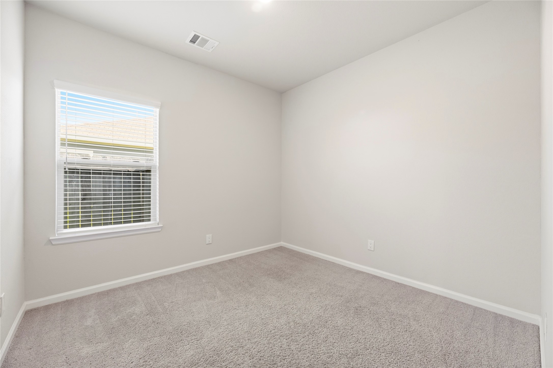 Create a comfortable sleeping space or a dedicated work-from-home setup in this additional room, finished with neutral walls and soft carpeting.