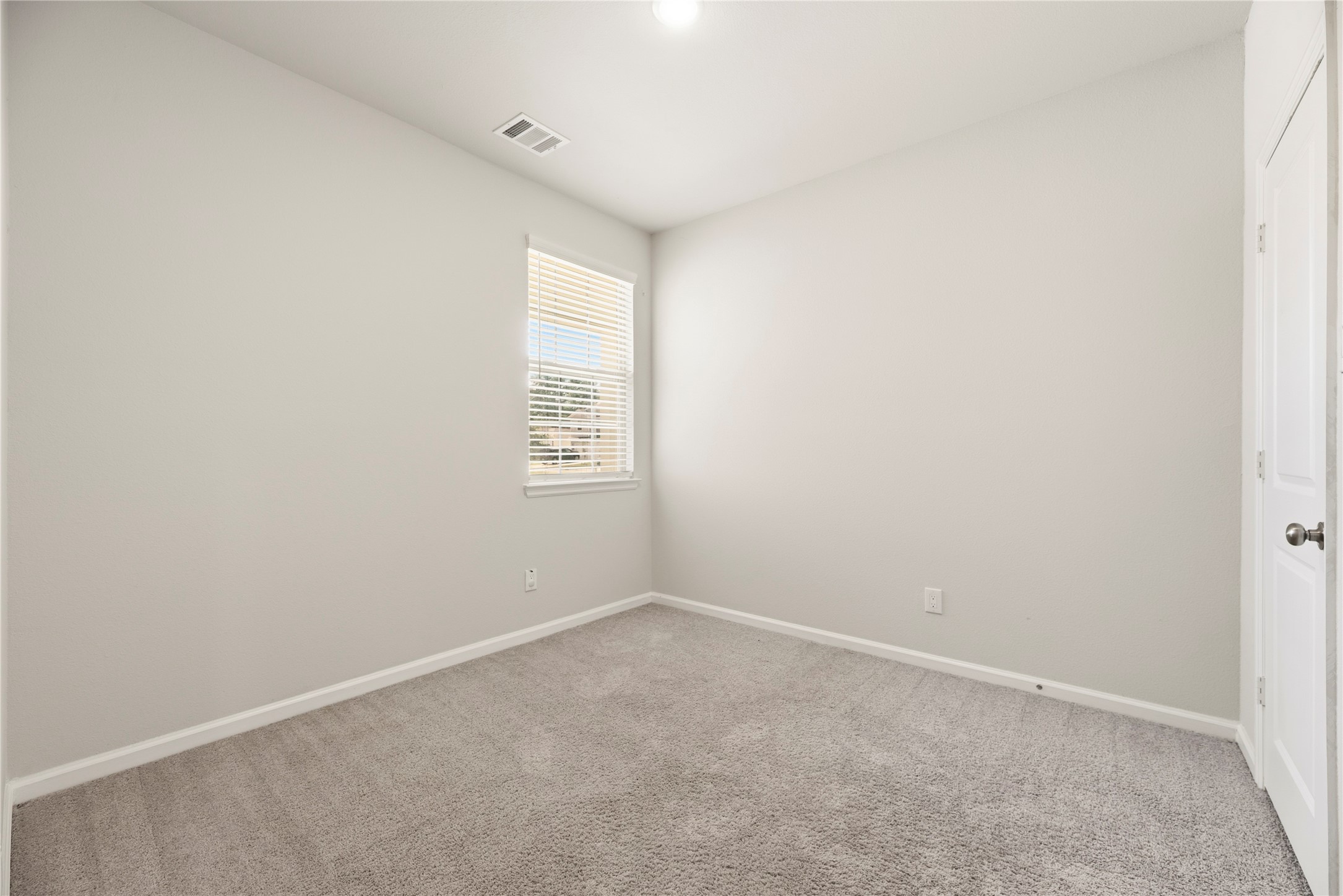 Another view highlights the rooms simple, adaptable layout, with closet doors and a window that make furniture placement easy to consider.