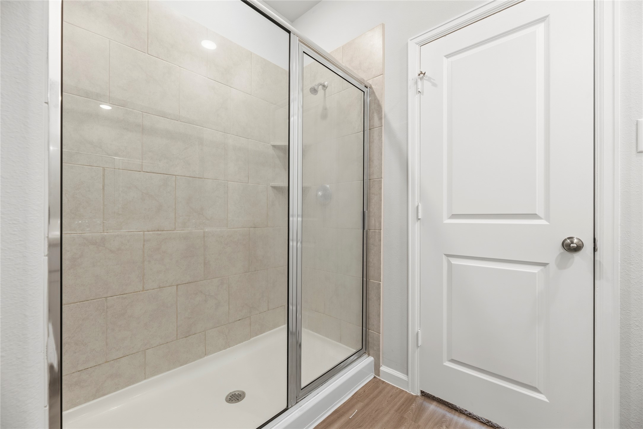 A glass-enclosed walk-in shower brings a clean-lined finish to the bathroom, with tile extending up the shower walls.