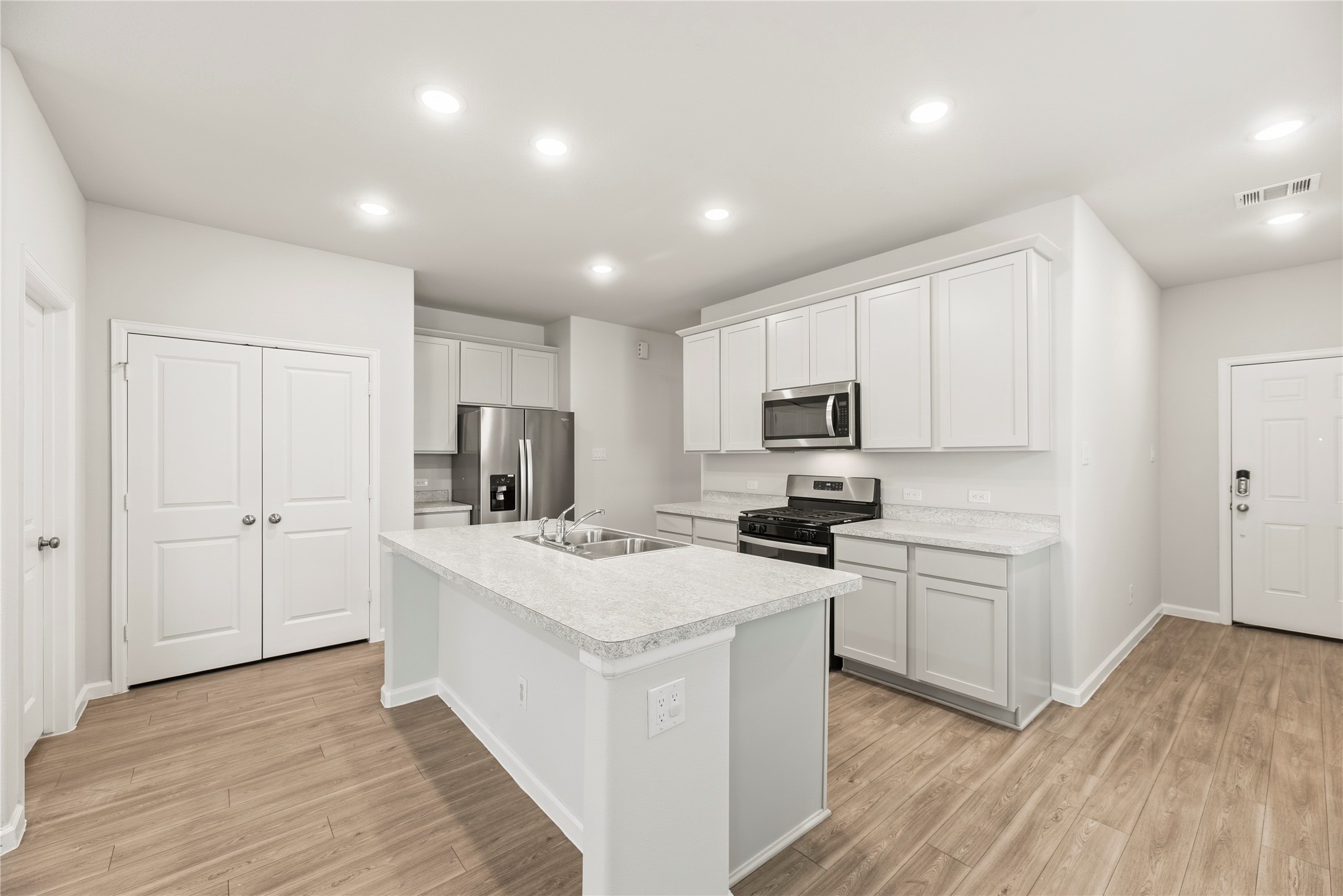 White cabinetry, stainless-steel appliances and an island create a bright, coordinated kitchen. The open layout keeps the cook connected to the rest of the room.