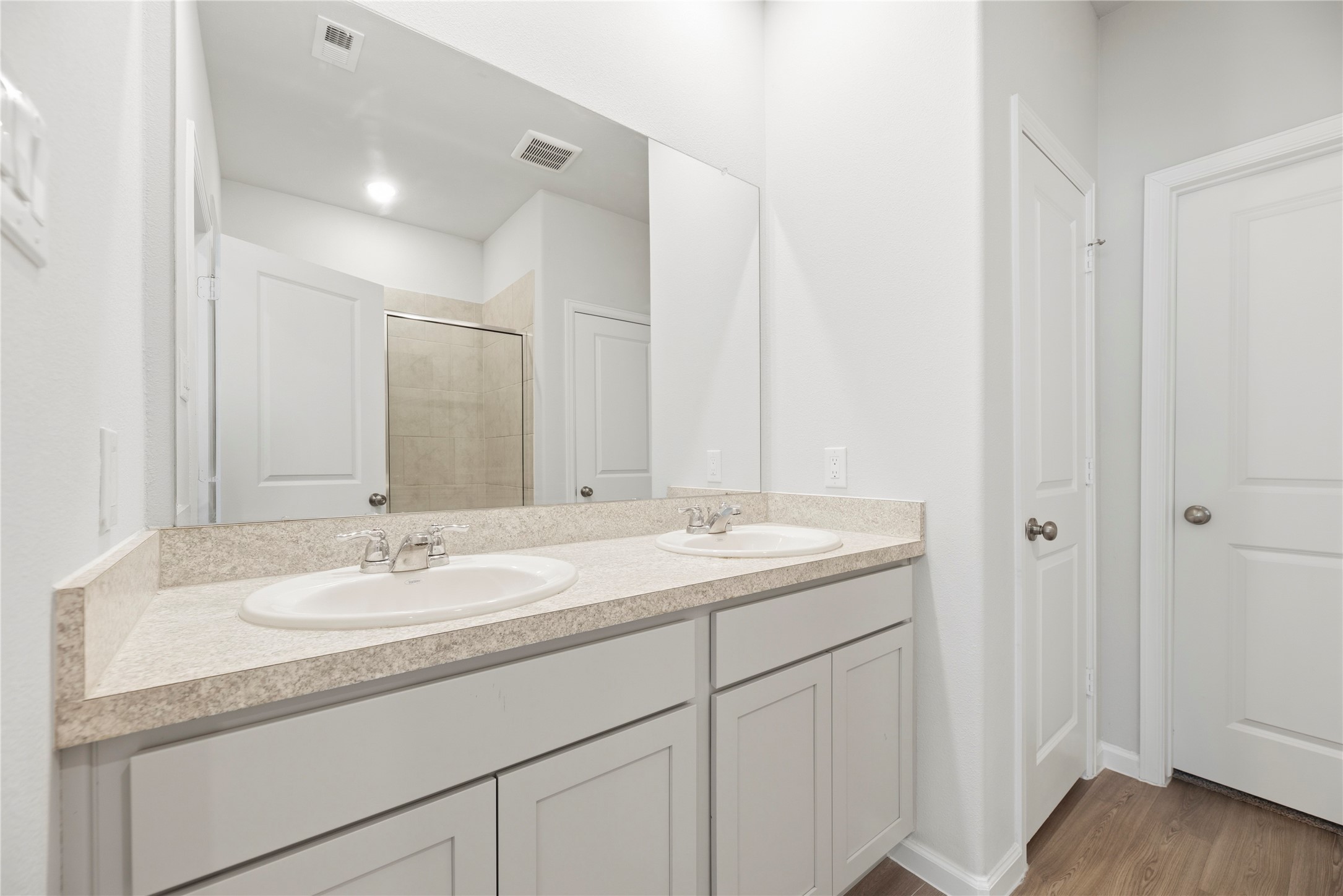 The bathroom vanity pairs counter space with cabinet storage to keep daily essentials close by, while the large mirror gives the space a bright, open feel.