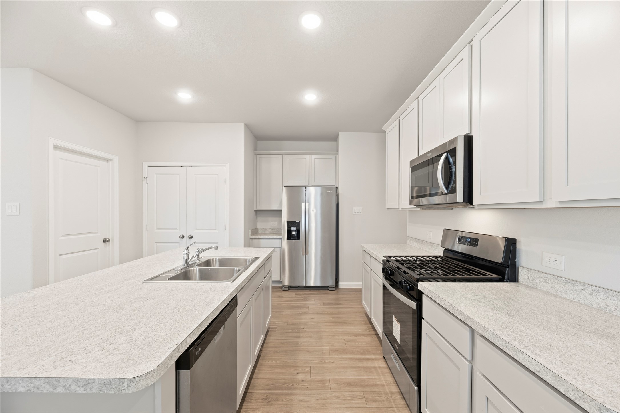 An efficient kitchen layout places the range, microwave and refrigerator around the island, with cabinet storage above and below the counters.