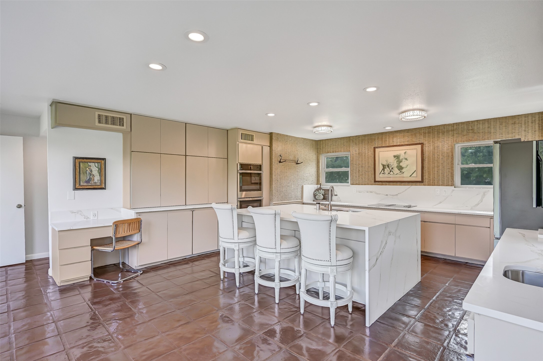 The beautifully renovated 17' x 21' kitchen offers an impressive combination of style & functionality, with extensive contemporary cabinetry, quartz countertops, an oversized waterfall island with bar seating & painted tile flooring. A built-in desk area adds convenience.