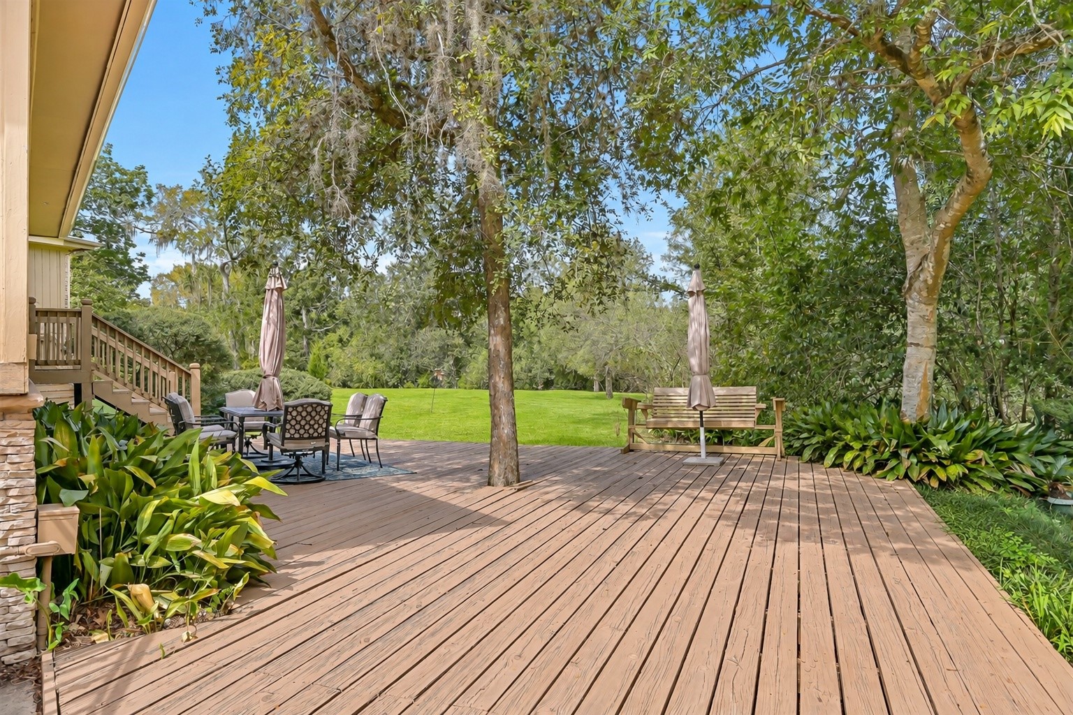 An expansive wooden deck stretches across the rear of the home, providing generous space for outdoor dining, seating & entertaining. Surrounded by mature shade trees, this inviting outdoor area overlooks the sprawling backyard, with plenty of room to enjoy the property's natural setting.