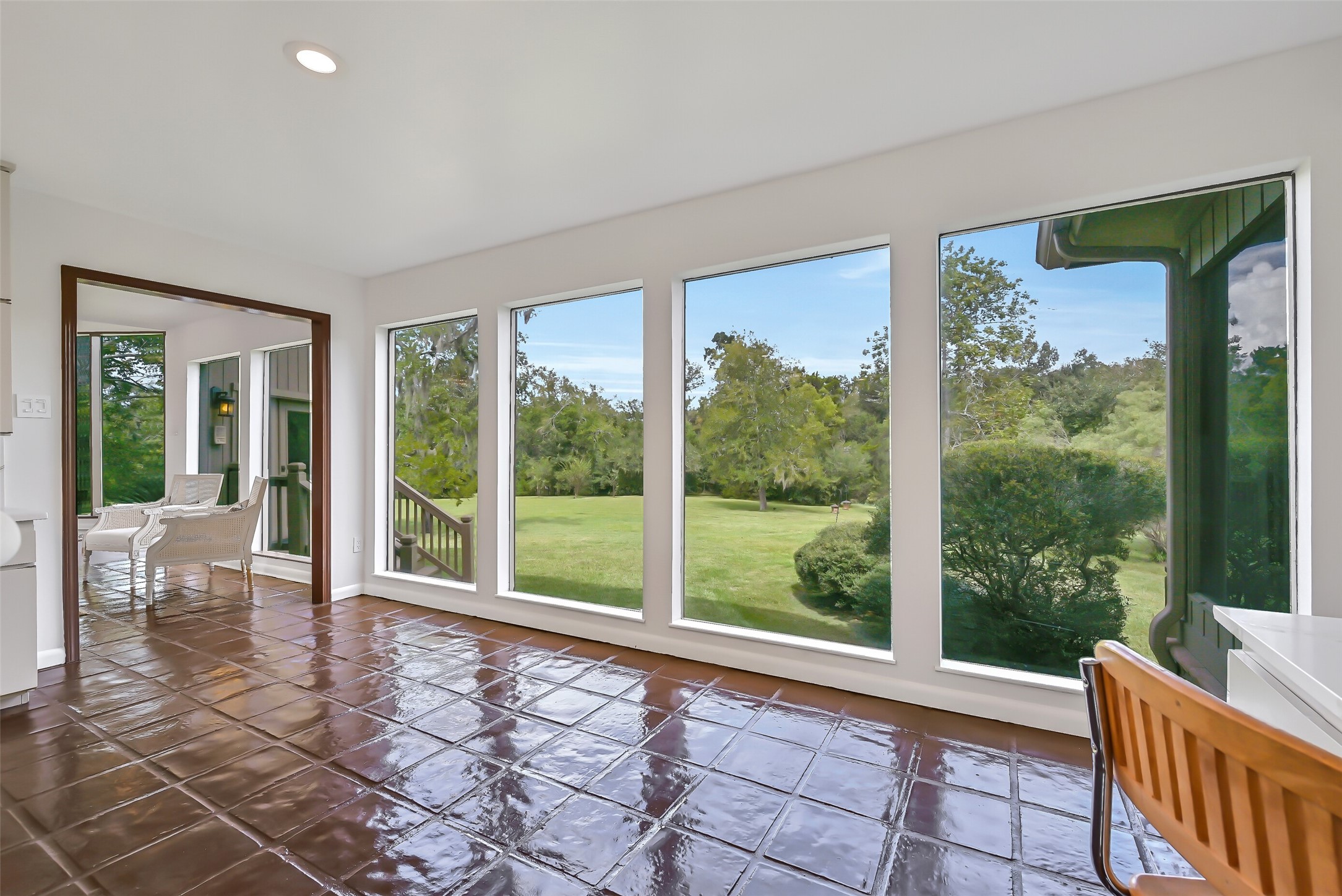 A wall of four oversized picture windows creates a beautiful backdrop for this flexible dining area adjoining the kitchen. Extending between the main living room & gameroom wing, this light-filled space offers room for a dining table while maintaining an open connection between the home's gathering areas.