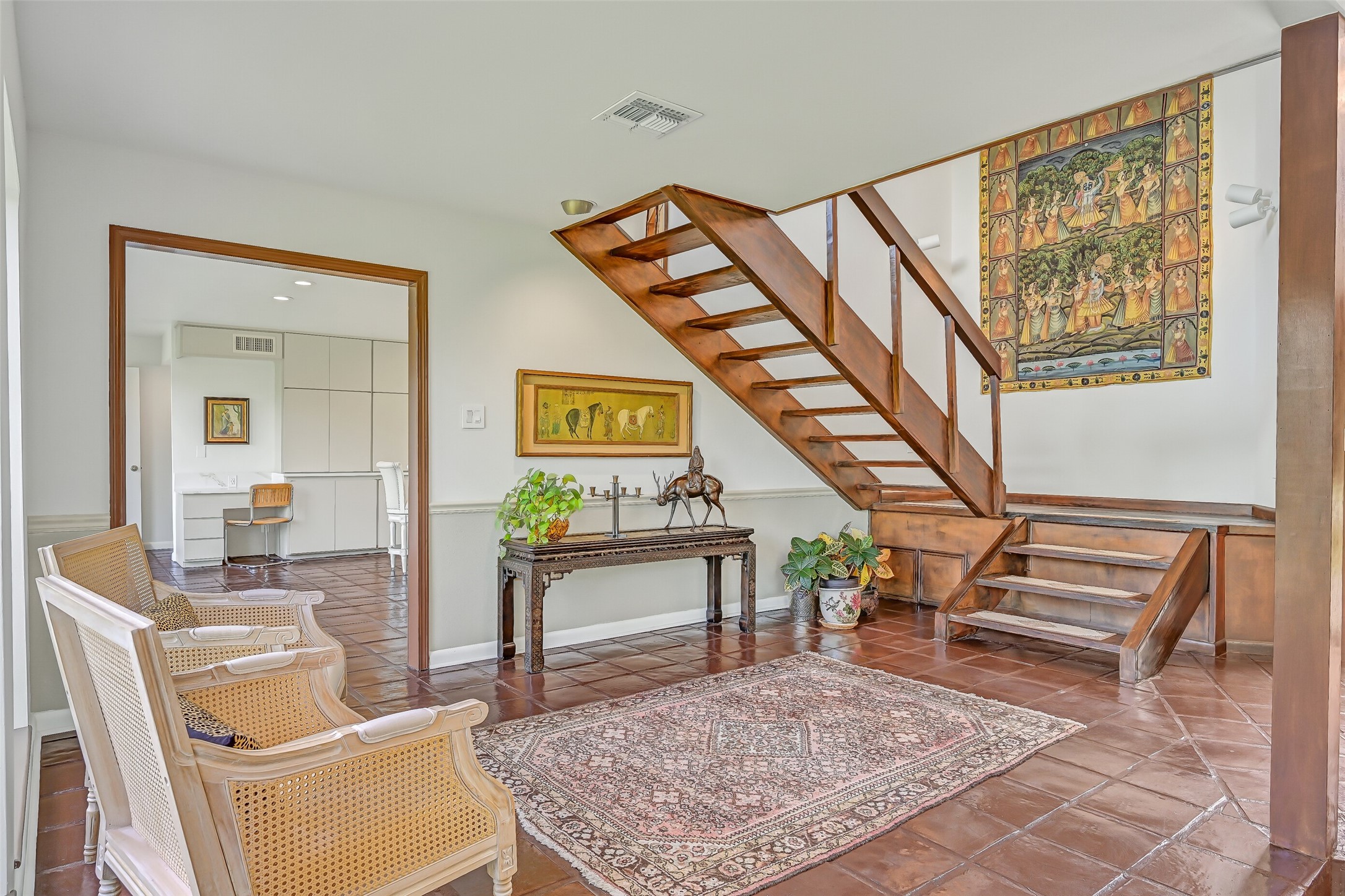 The open-riser wooden staircase adds architectural character to this spacious entry hall, where rich wood accents & tile flooring reflect the home's distinctive design. Just beyond the wide doorway, the beautifully renovated kitchen awaits, featuring extensive cabinetry & an oversized island.