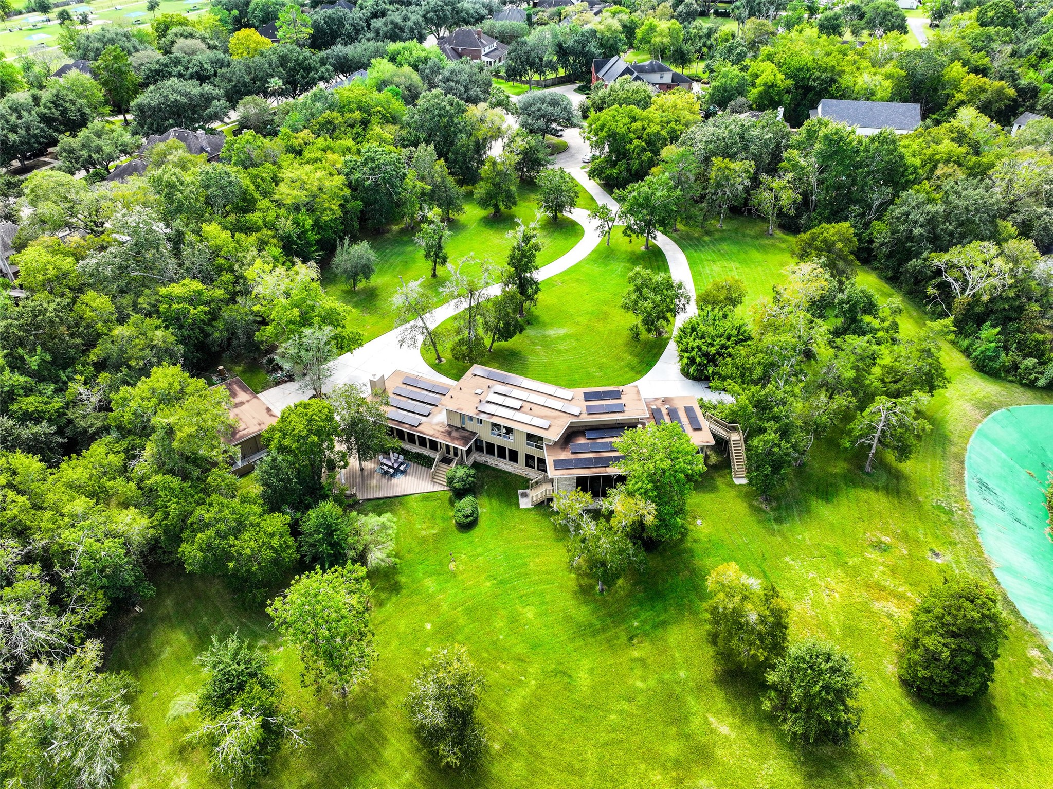 A different perspective highlights the home's distinctive rooflines, expansive rear deck & large windows overlooking the property. Mature trees provide a beautiful backdrop, while the open lawn offers abundant space for outdoor recreation, gardening or simply enjoying the grounds.