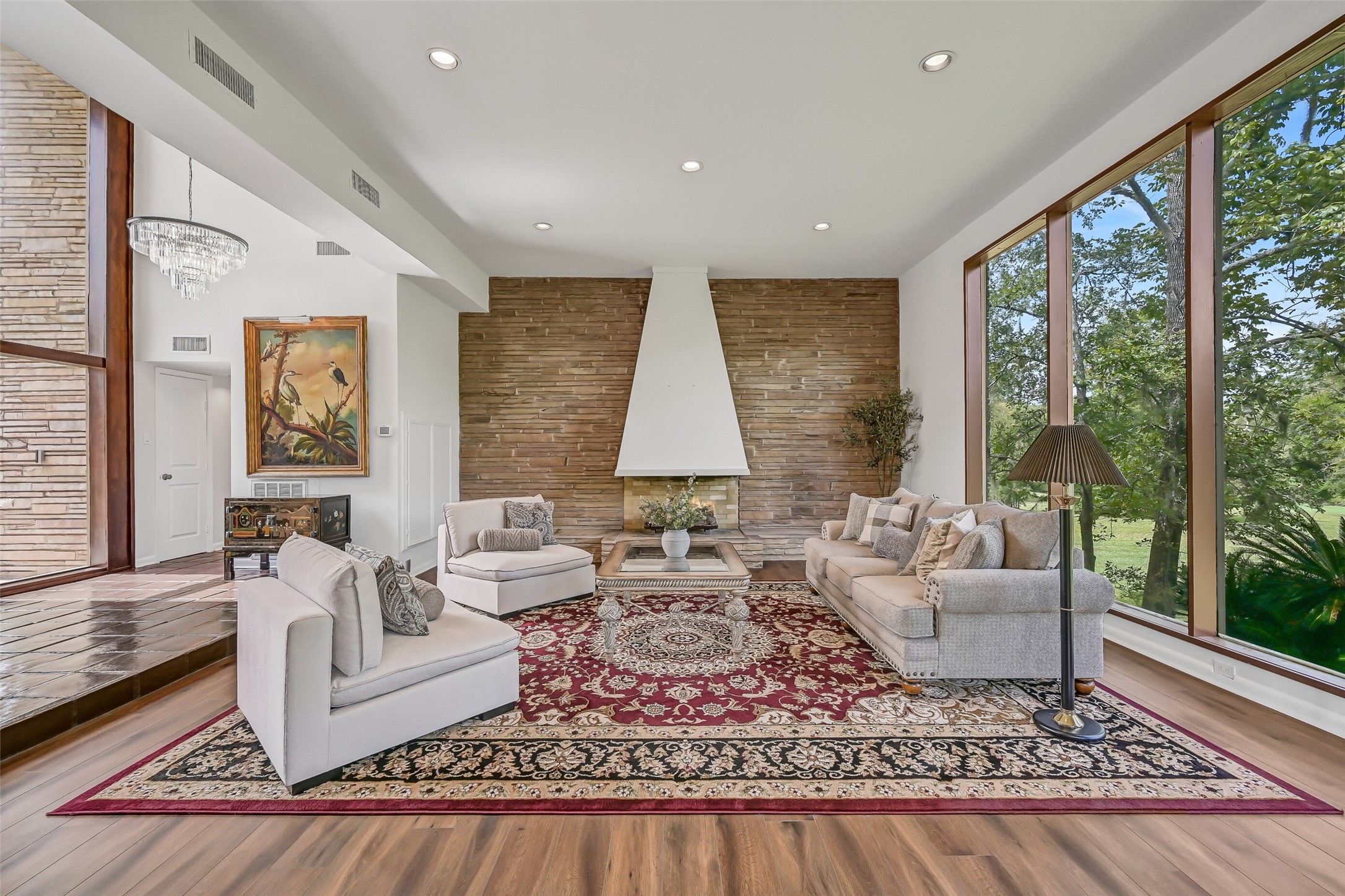 A closer look at the distinctive gas-log fireplace reveals its impressive stone accent wall, sculptural stucco hood & extended raised hearth. This dramatic architectural feature anchors the spacious living room, combining the home's original contemporary character with its updated interior finishes.