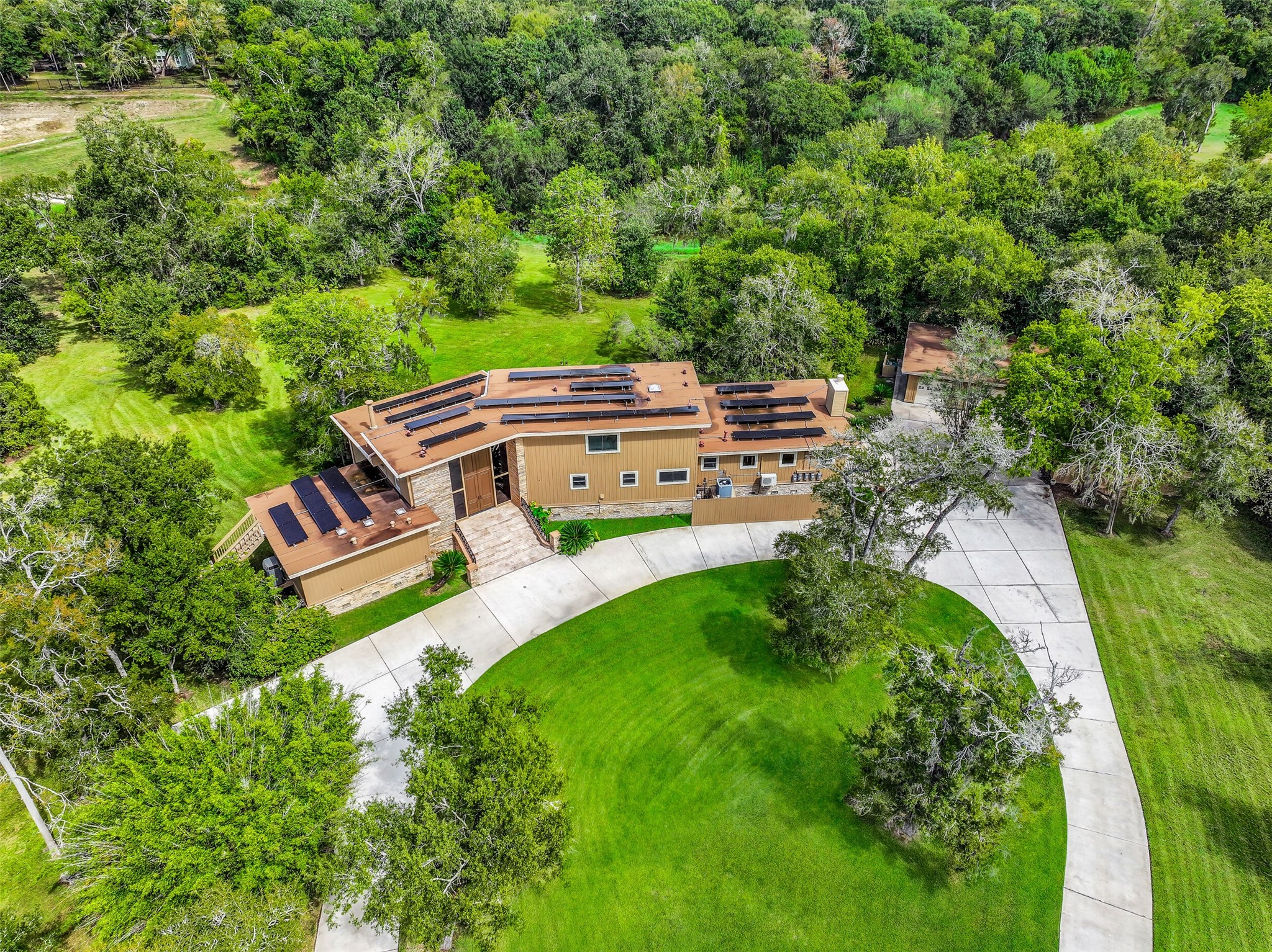 From above, the property's unusual configuration becomes clear, with its private approach opening into a generous homesite bordered by natural surroundings. Cowart Creek winds through portions of the acreage, adding to the landscape just minutes from the center of Friendswood.