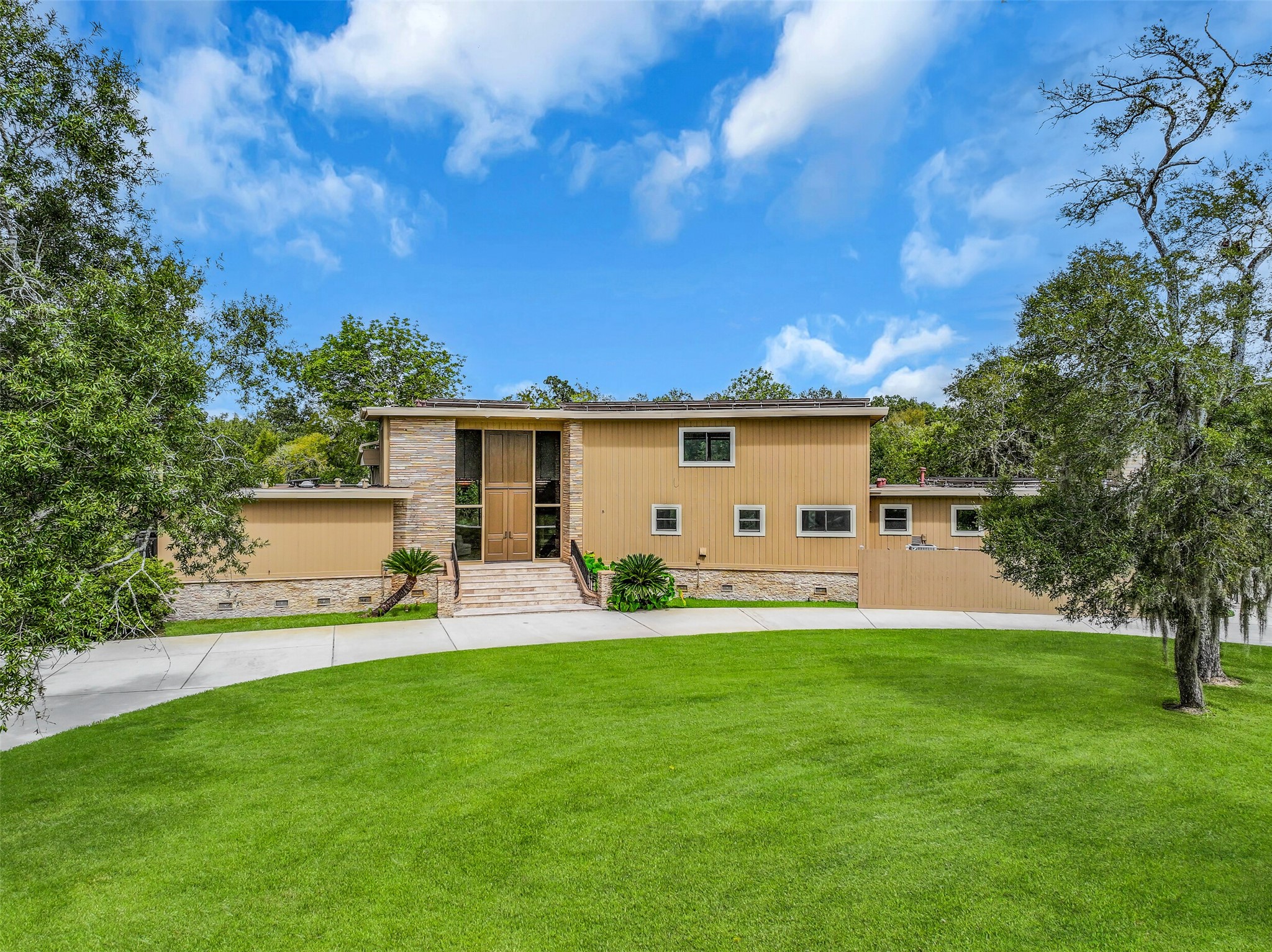 An inviting approach showcases the home's unique architectural design, with stone exterior accents, tall double entry doors & extensive windows. The grand entrance is reached by a travertine staircase with iron railings, creating a memorable introduction to this one-of-a-kind property.