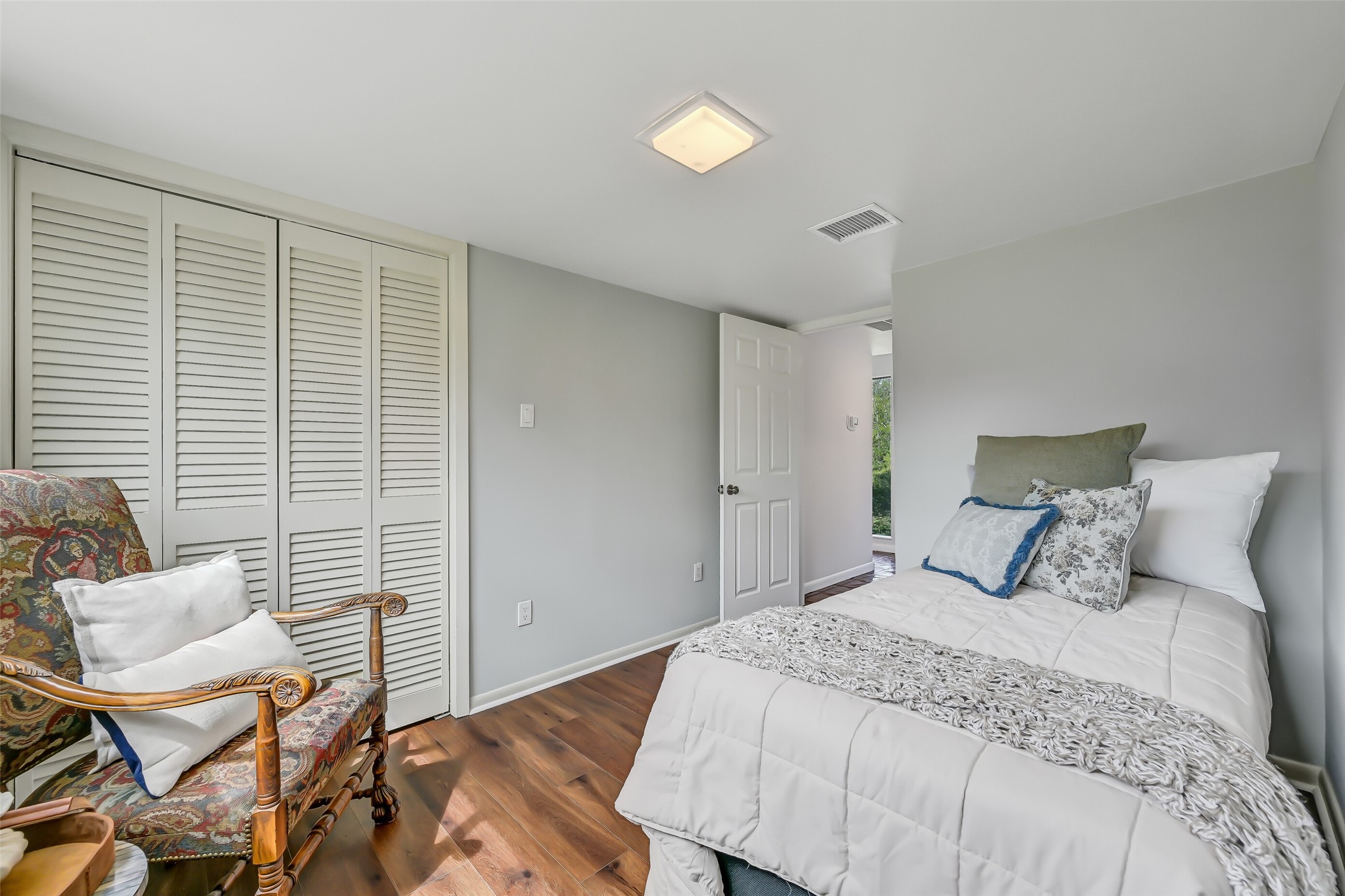 Located in the wing between the kitchen & gameroom, this secondary bedroom features luxury vinyl plank flooring, neutral paint, updated lighting & a window overlooking the grounds. A nearby full bathroom adds convenience for guests.