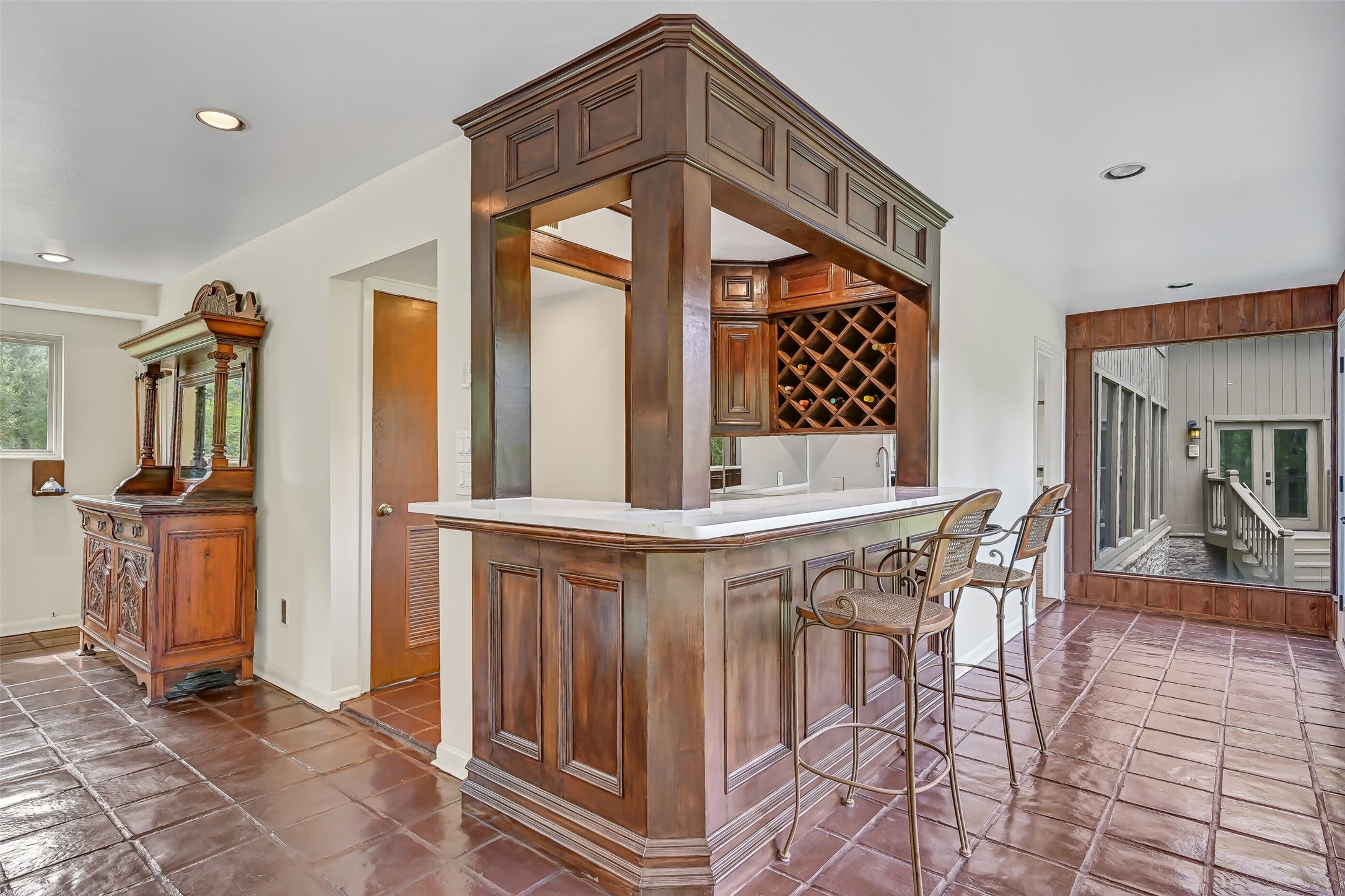 Entering the expansive 23' x 23' gameroom, a custom wood wet bar welcomes you with rich paneled cabinetry, quartz-look countertops, built-in wine storage & bar seating. Complete with a sink & beverage refrigerator, this inviting gathering space is ideal for hosting friends & family.