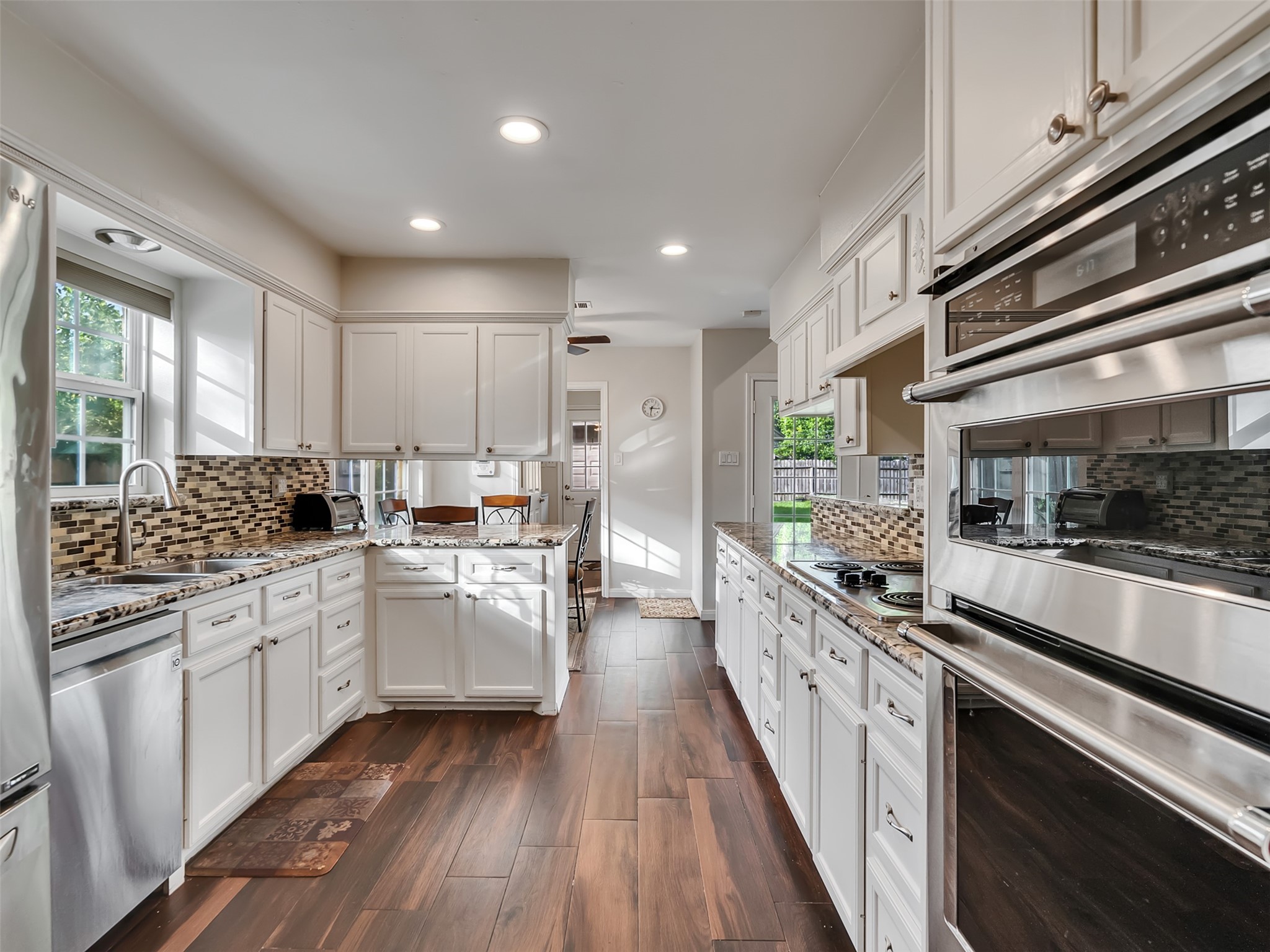 This beautiful kitchen features warm wood-look flooring, a stunning glass tile backsplash, and gorgeous granite countertops.