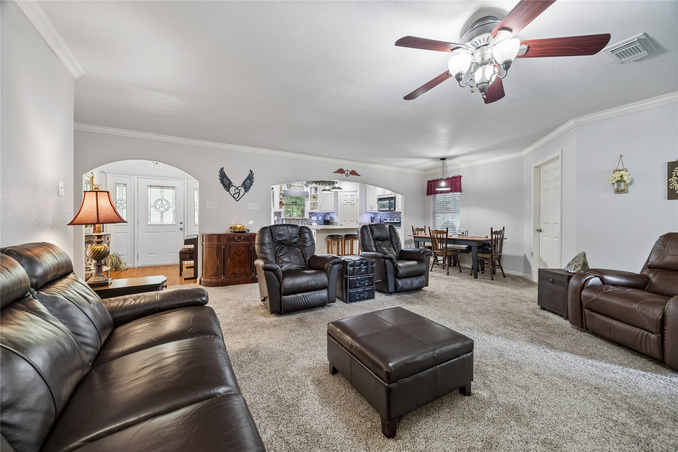 A seamless view of the living room, front entryway, and a glimpse into the kitchen