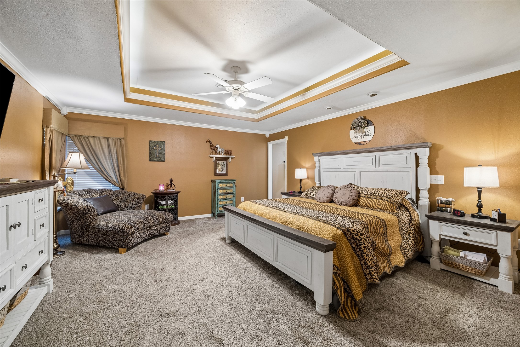 The primary suite showcases a beautiful tiered ceiling design and a central ceiling fan
