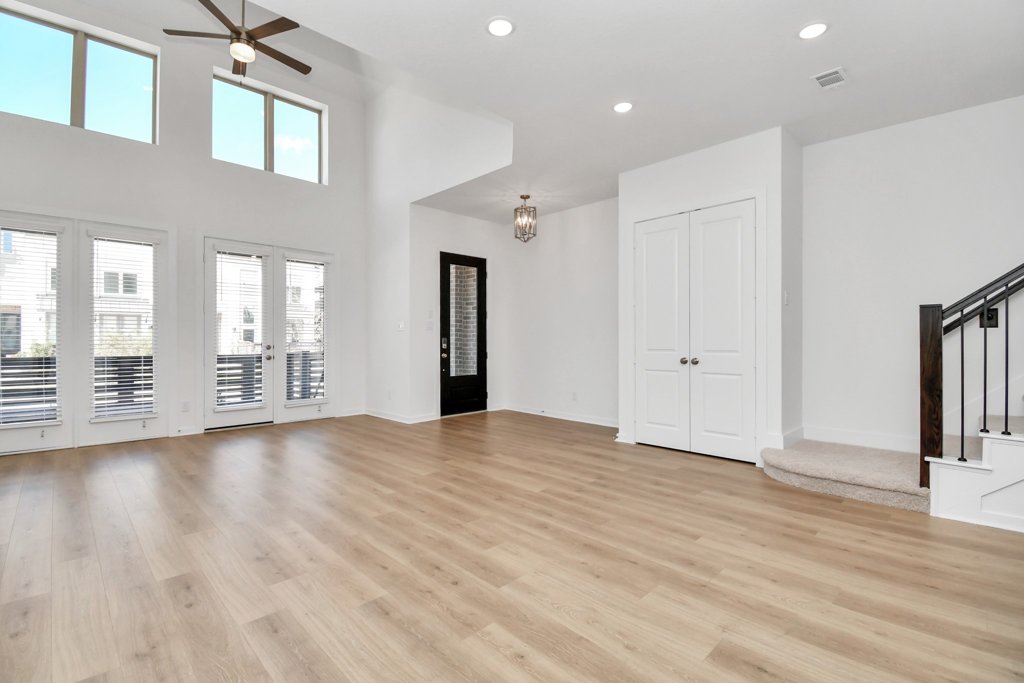 The living room is bright and spacious, featuring soaring high ceilings that amplify natural light for an open, airy feel.