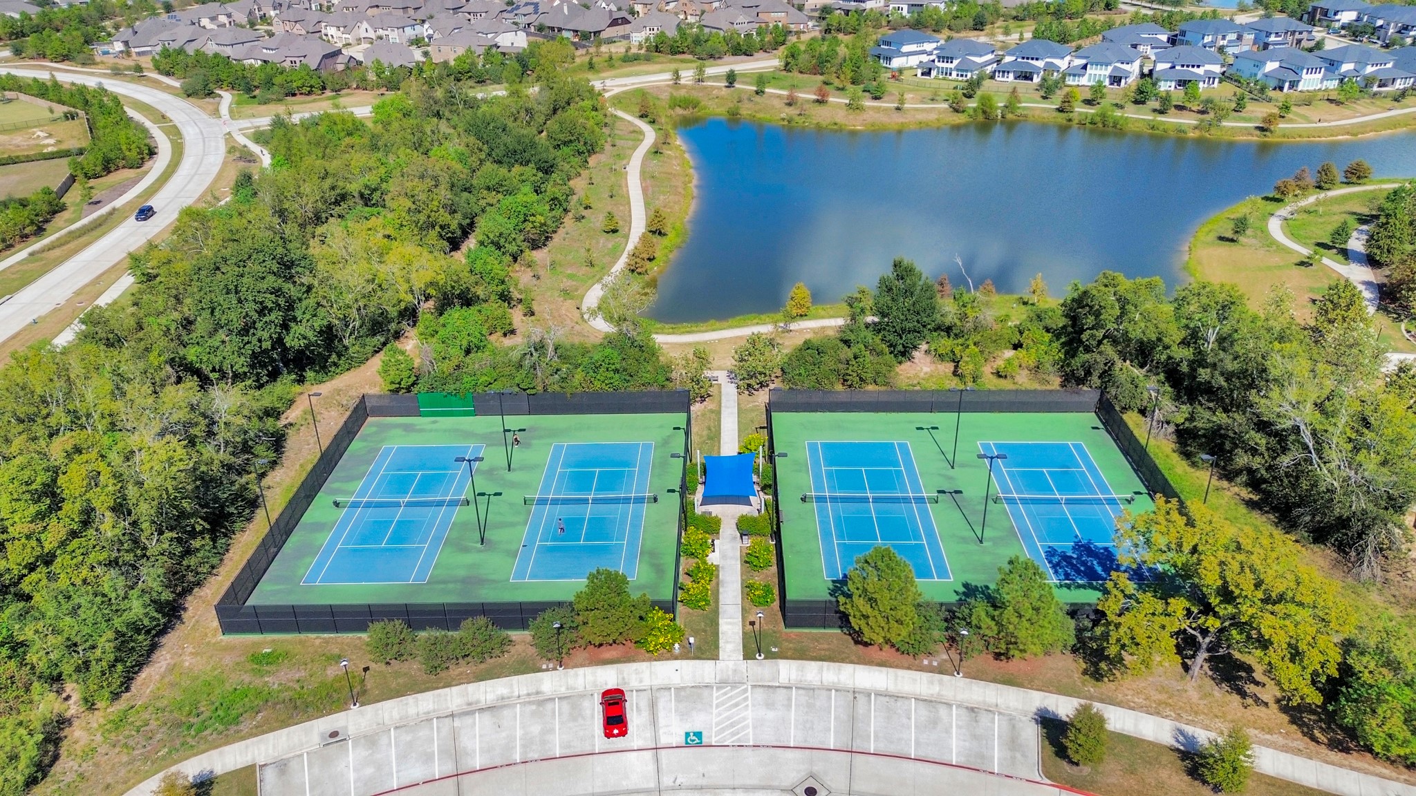 The aerial view highlights the community tennis courts, showcasing their well-maintained surfaces and strategic layout within the neighborhood, perfect for recreational play.