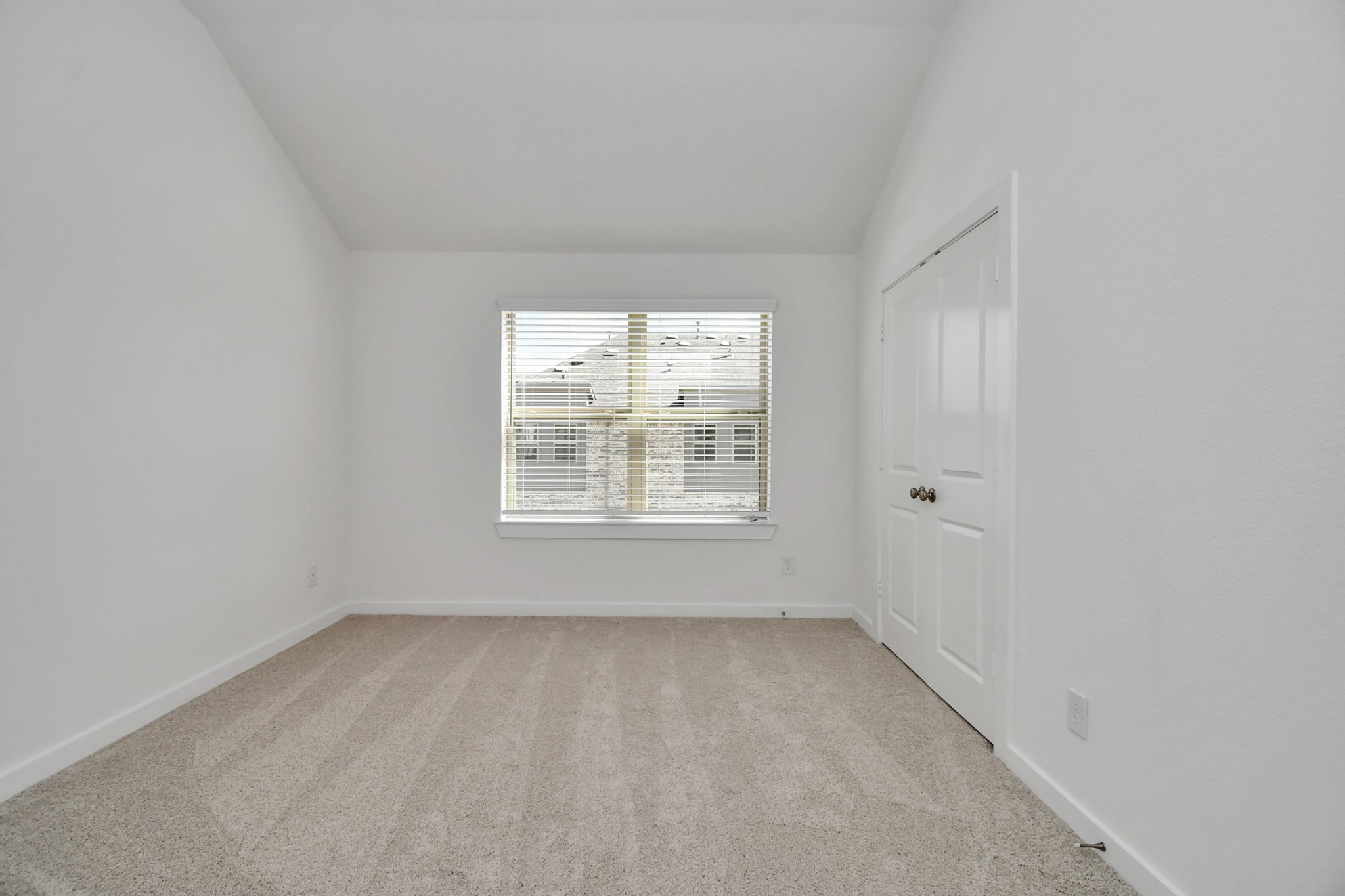 The secondary bedroom features a bright white palette and soft carpet, creating a cozy and inviting atmosphere.