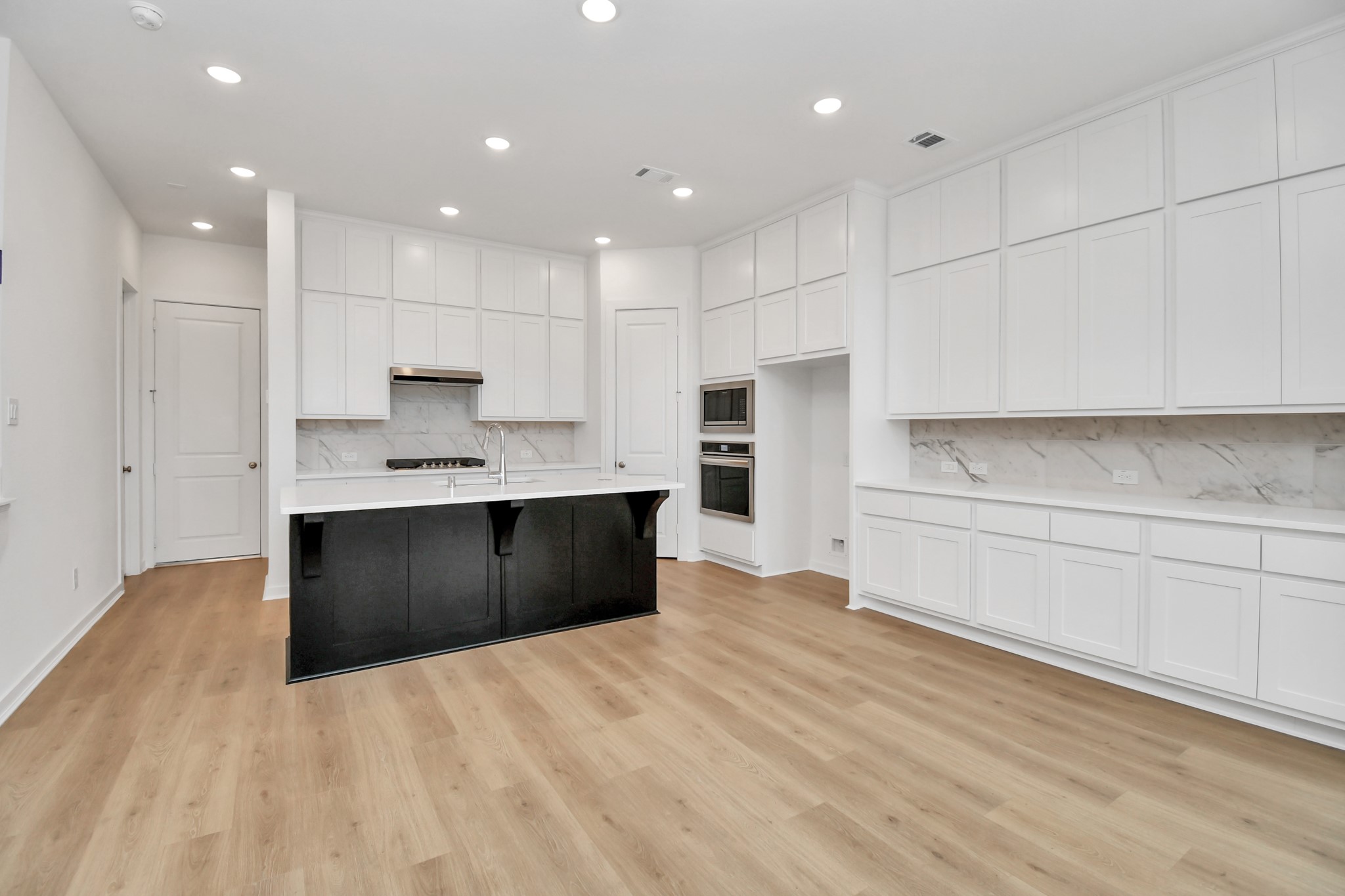 The kitchen, open to the living room, features ample cabinet storage and sleek stainless steel appliances for a modern touch.
