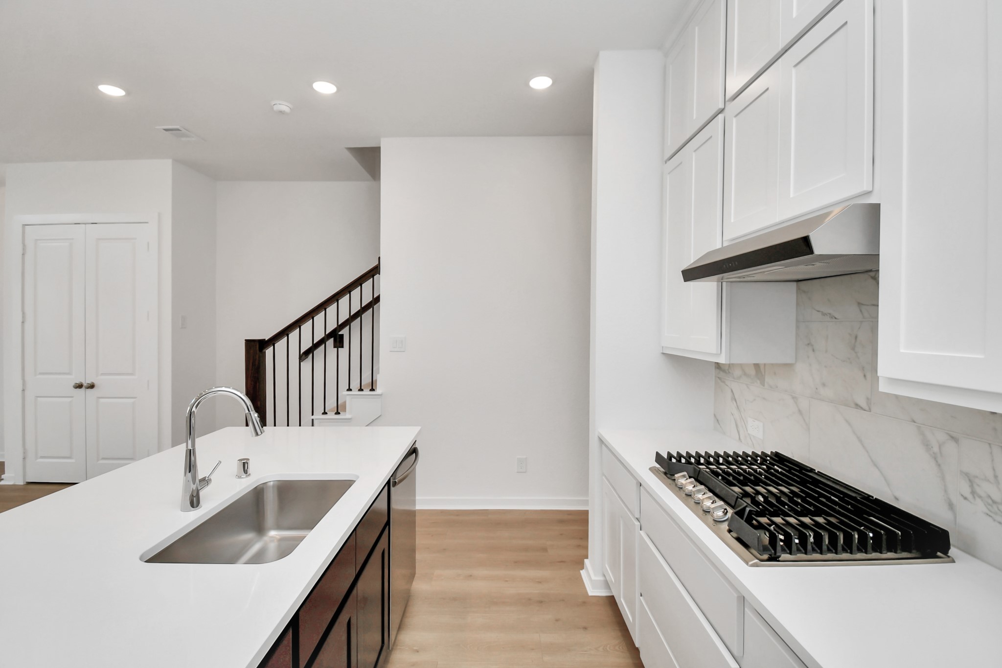 The kitchen offers a closer look at its stylish design, featuring a gas cooktop, ample cabinetry, and stainless steel appliances, blending functionality with modern elegance.